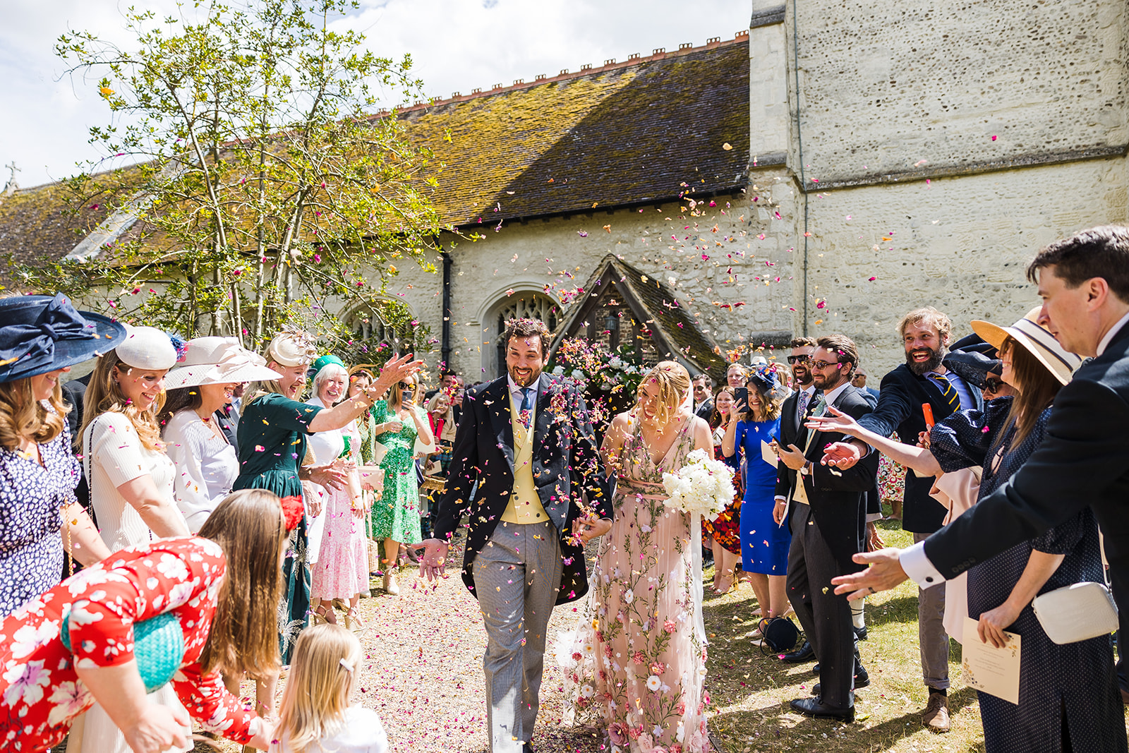 A couple being showered in confetti outside the Church of St Andrew and St Mary, Grantchester