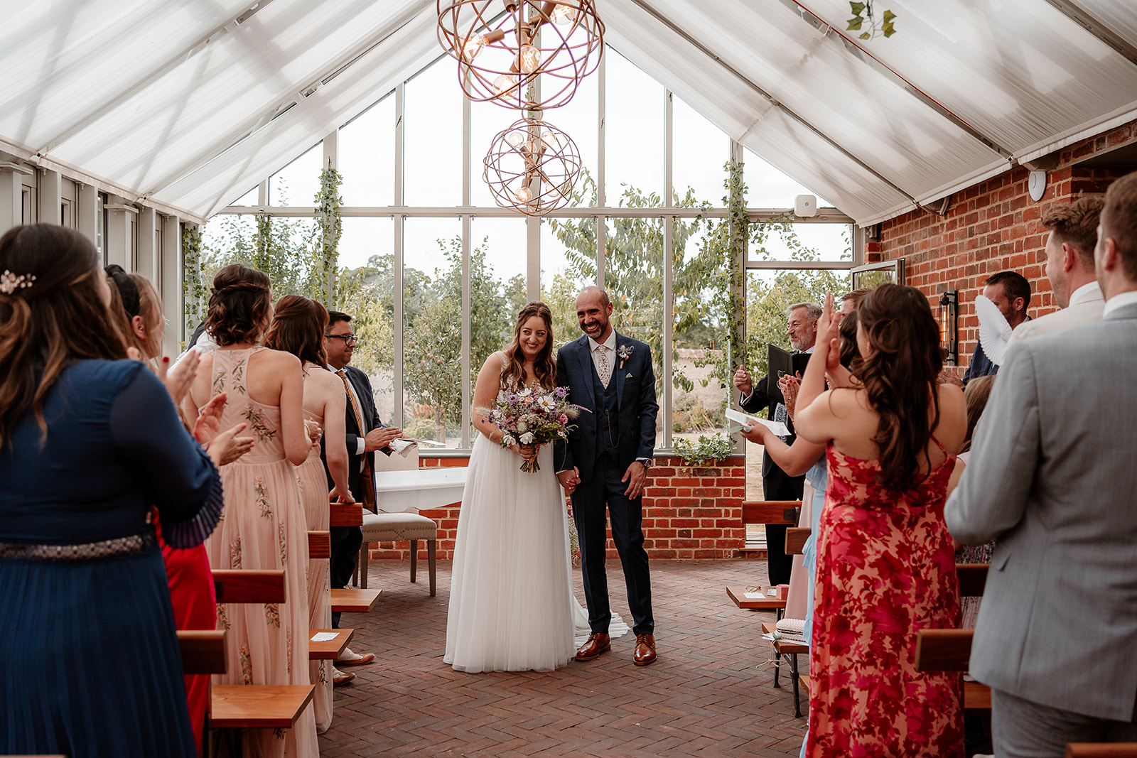 A couple say their vows together in the Glasshouse at their summer Syrencot wedding. 