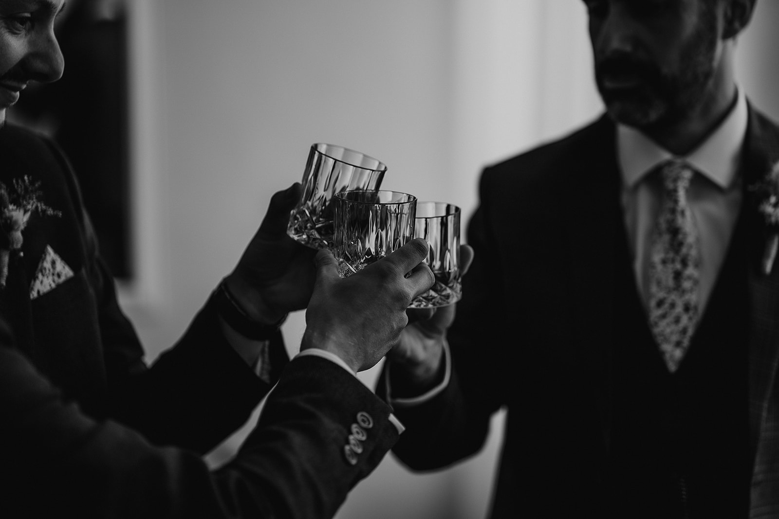 The groom and groomsmen toast with glasses of whiskey at a summer Syrencot wedding. 
