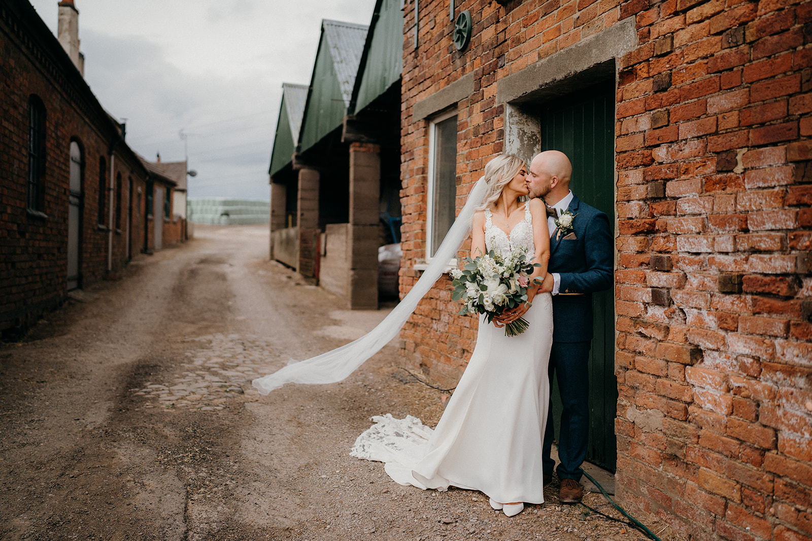 Bride and groom outside the barns embracing with a kiss