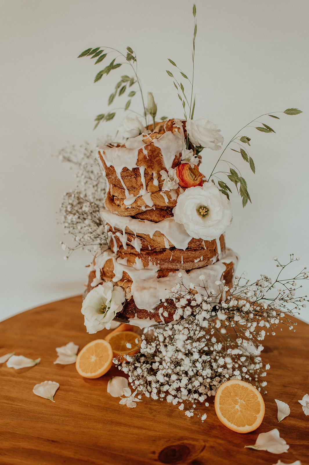 tiered Cinnamon Roll Wedding Cake garnished with citrus and florals during kinn guesthouse downtown milwaukee wedding