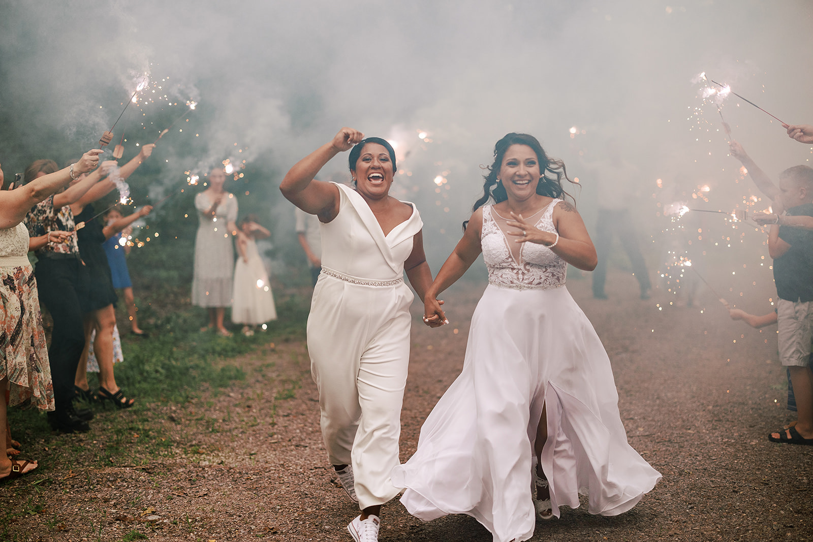 same sex couple runs through a sparkler tunnel on their wedding day in central wisconsin