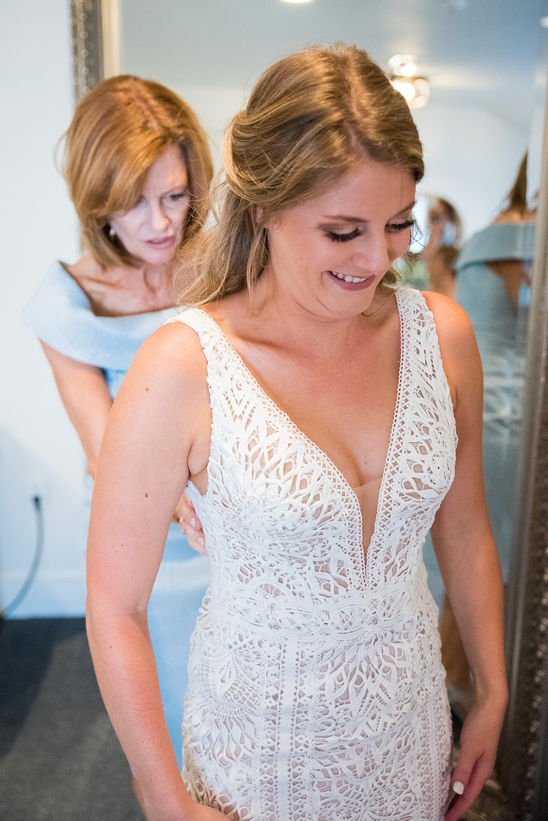 Bride's mother helps her button her wedding dress.