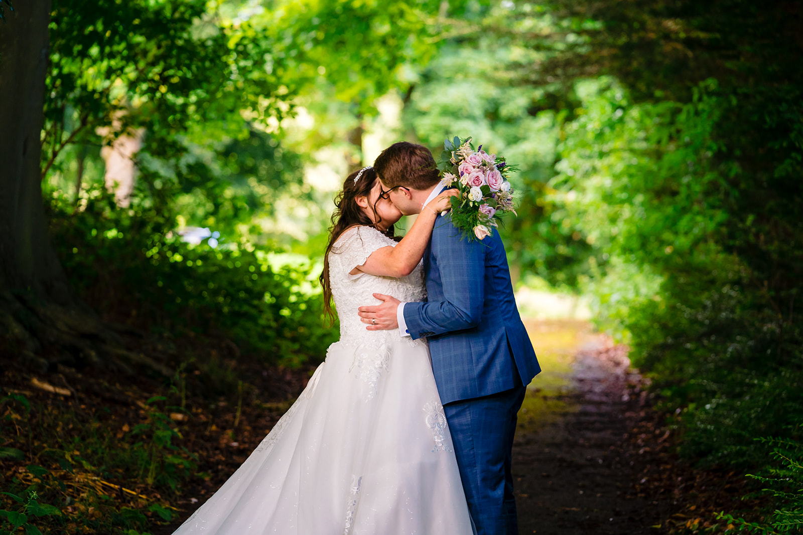 Bride and groom kiss each other in the grounds of hollins hall