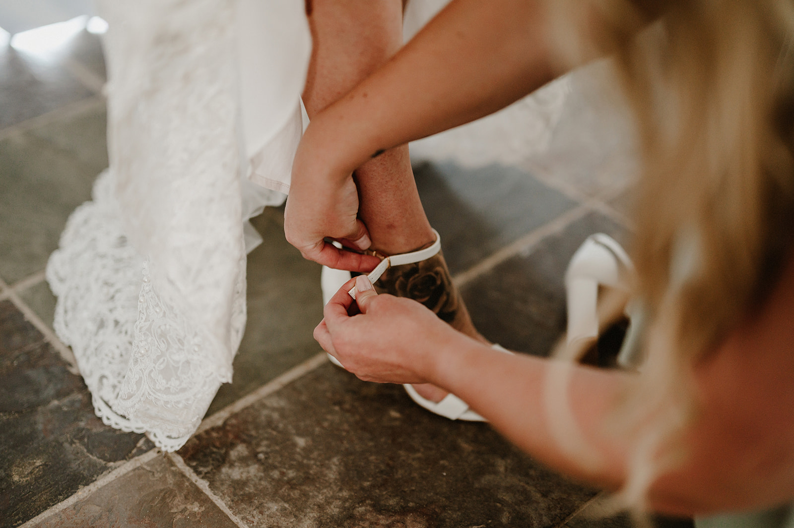 a bride at villiers barn having her wedding shoes laced up