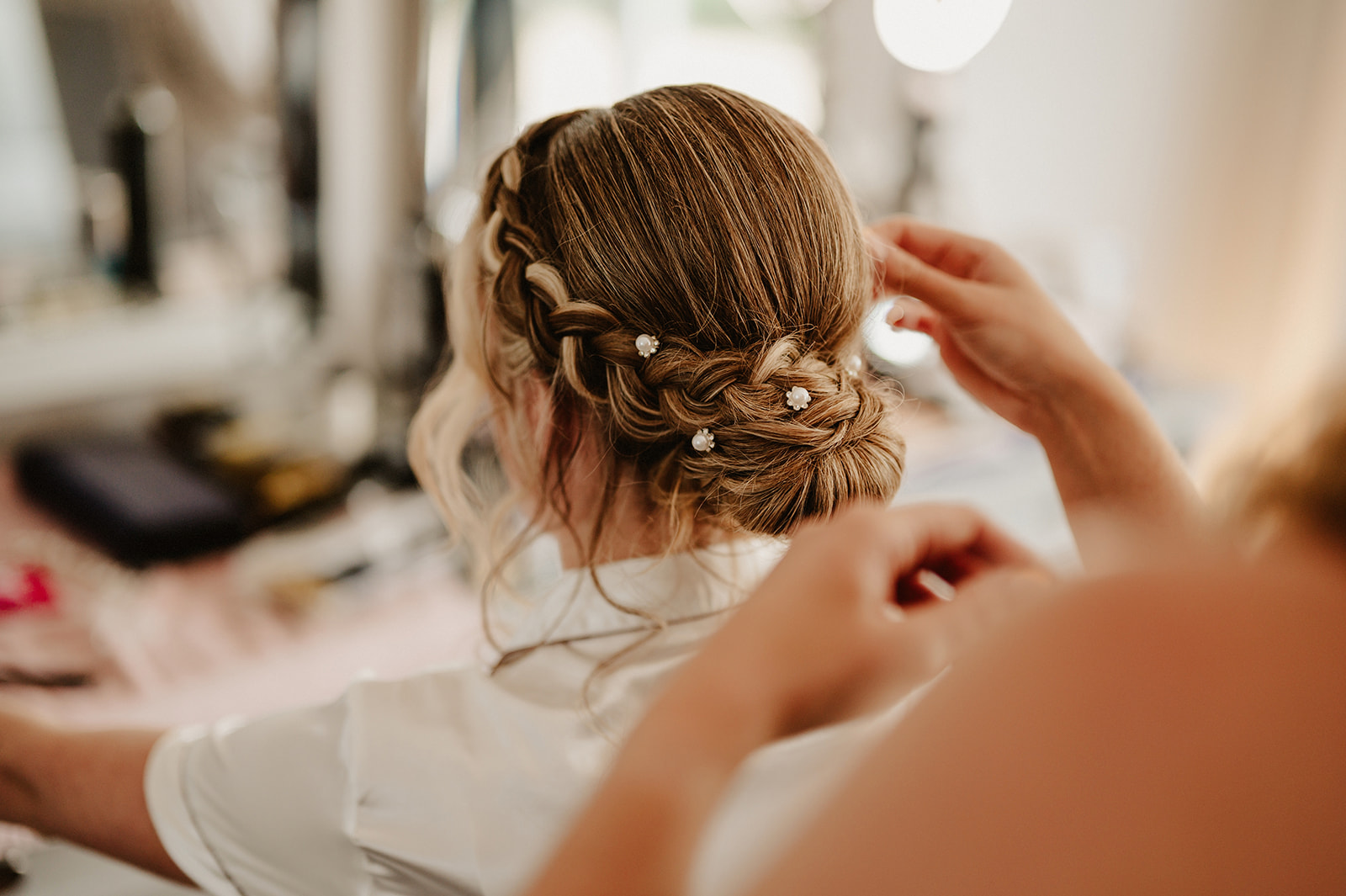 colour photo of a hairdresser putting the finishing touches to a brides hair at villiers barn