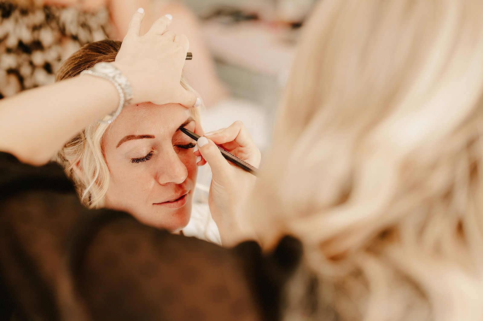 a rule of thirds wedding photograph of a make up artist placing make up on a bride at villiers barn
