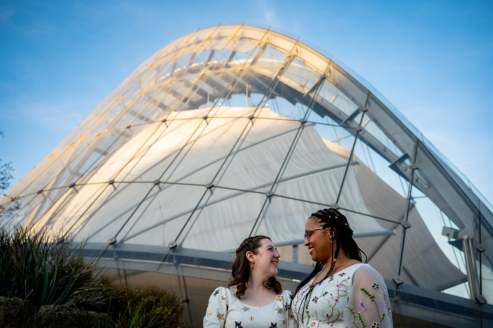 two brides standing in front of a glasshouse at Kew Gardens