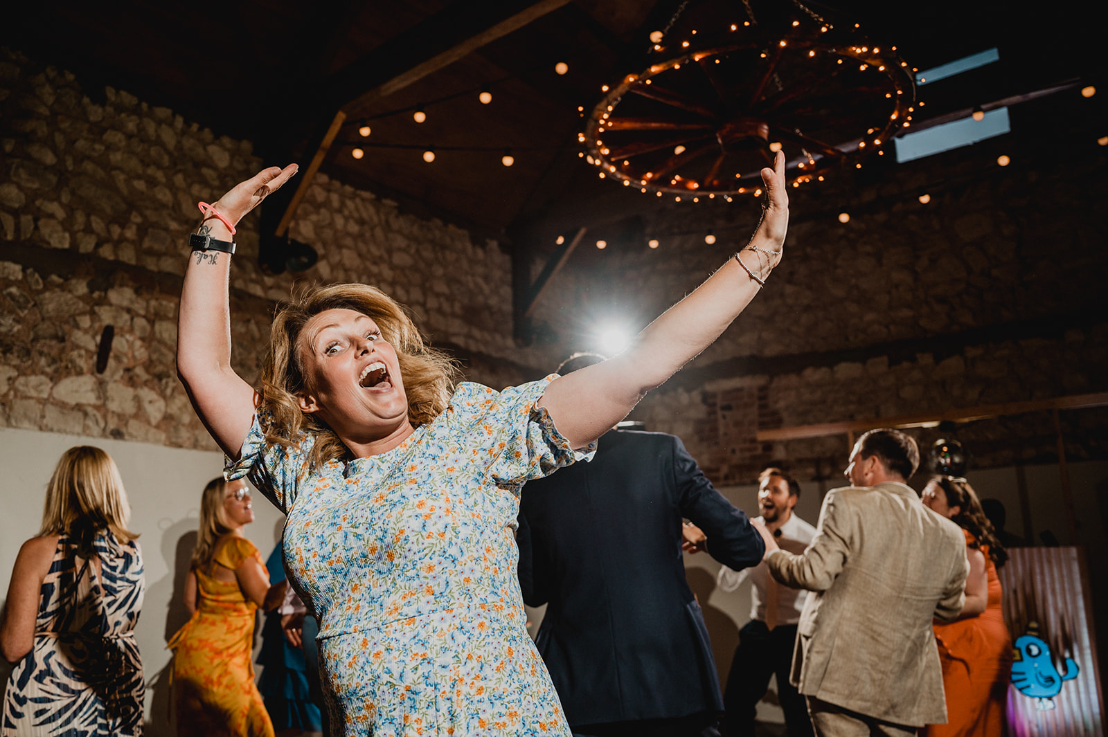 A guest at a wedding throws her hands in the air during a disco