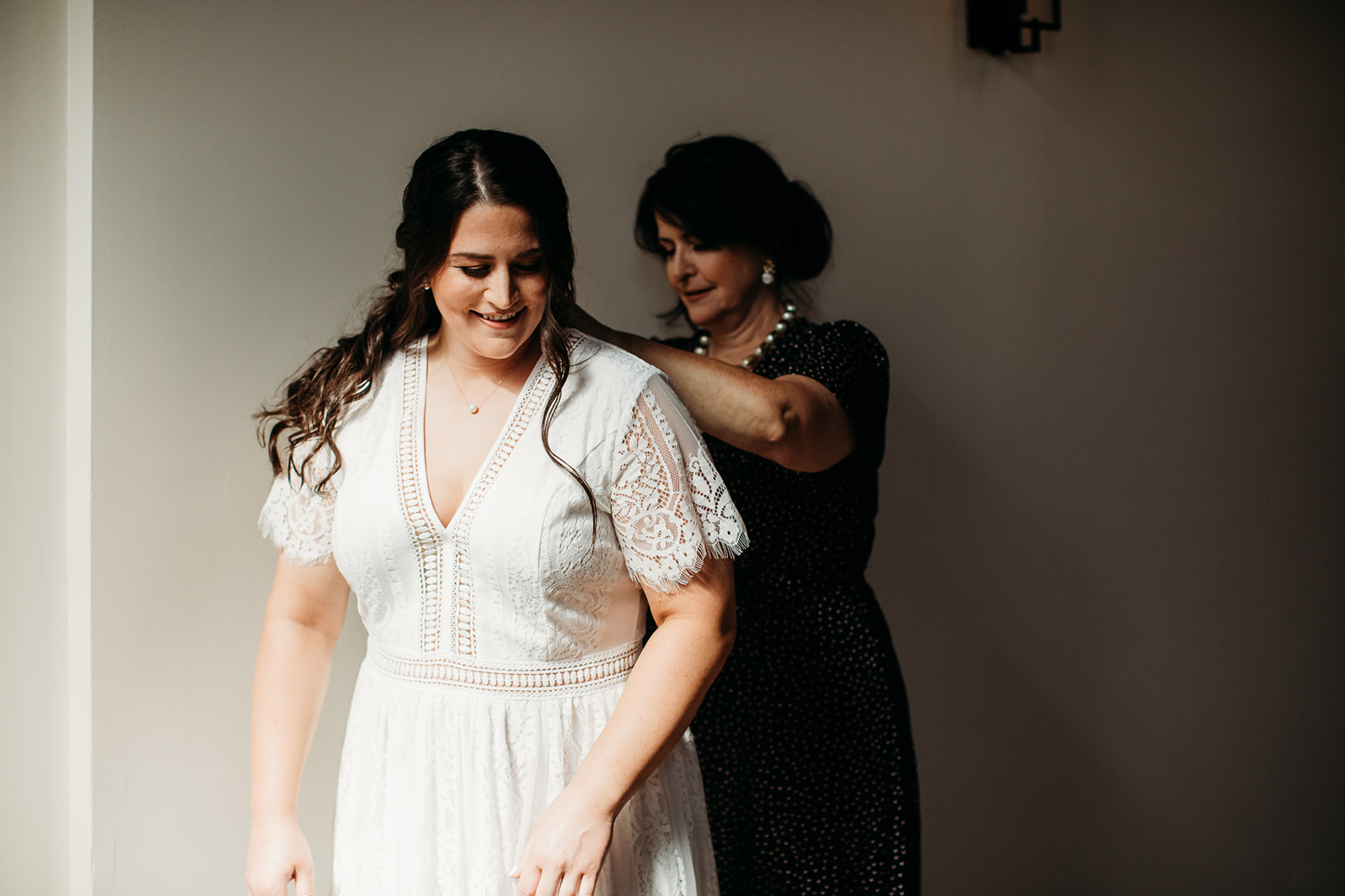 Bride's mother helps her get into her wedding dress