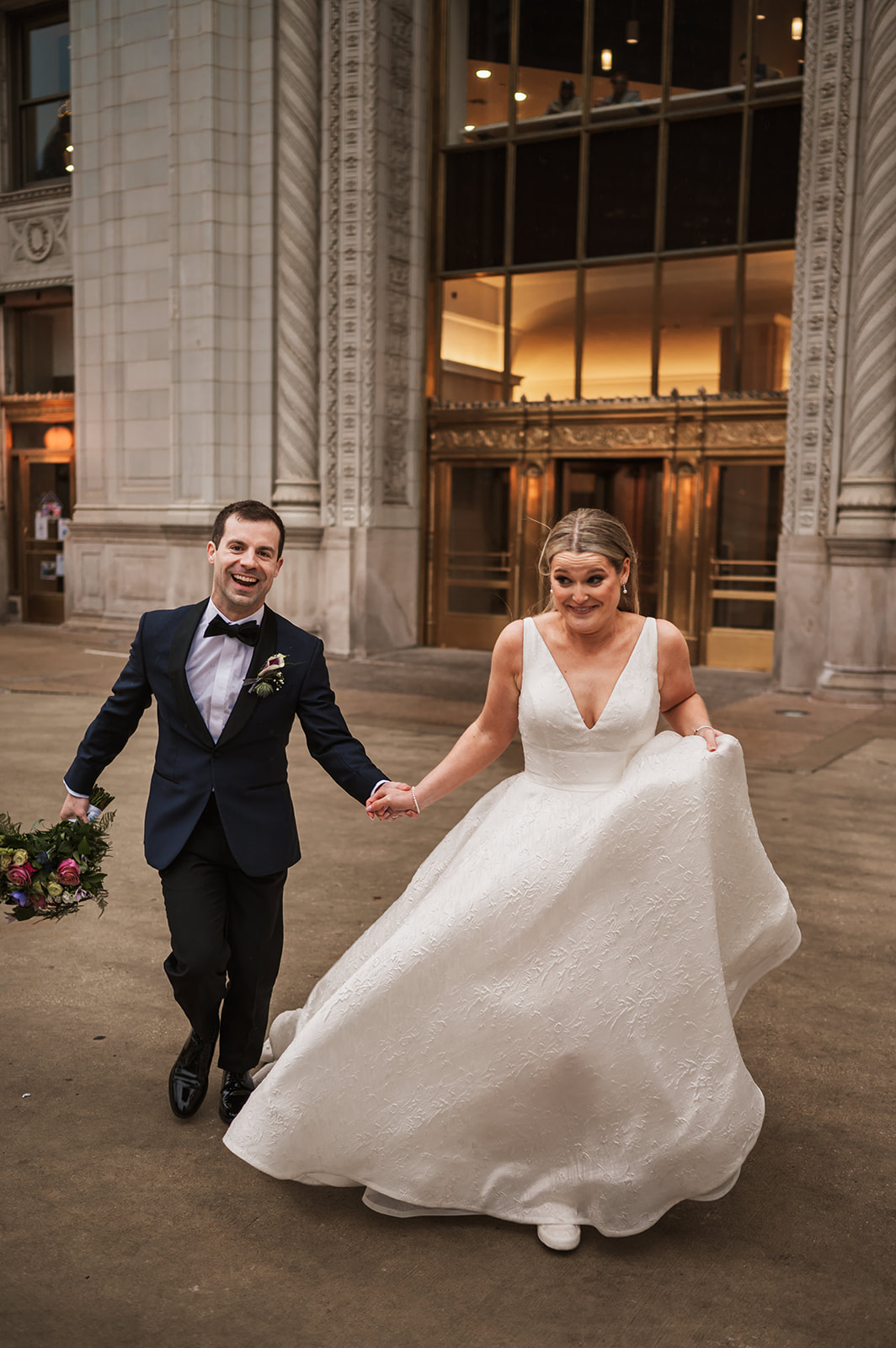 Bride and groom at the end of the winter on riverwalk by the Wrigley building chicago running