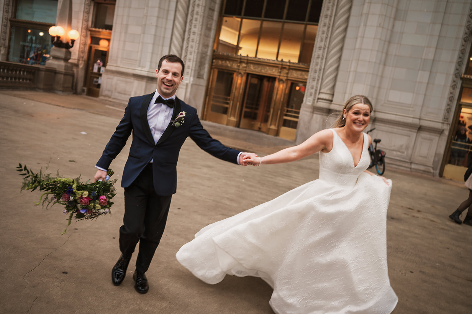 Bride and groom at the end of the winter on riverwalk by the Wrigley building chicago running