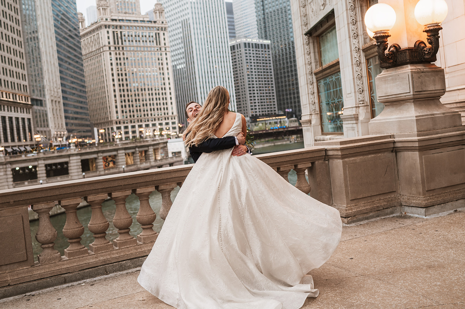 Bride running and jumping on a groom at the end of the winter on riverwalk by the Wrigley building chicago