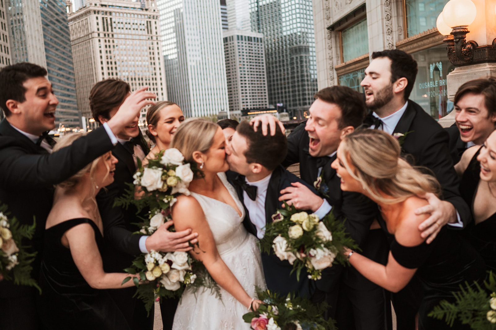 wedding party at the end of the winter on riverwalk by the Wrigley building chicago group hug
