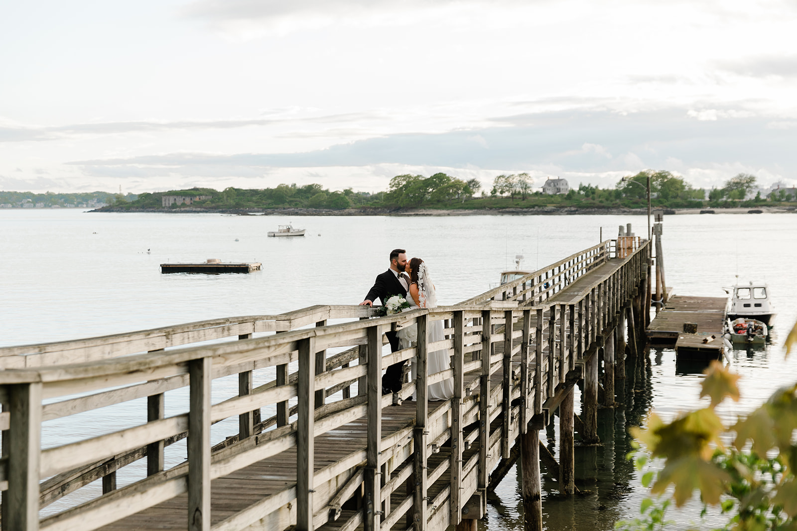 couple portraits on a pier at peaks island maine during a calm water sunset