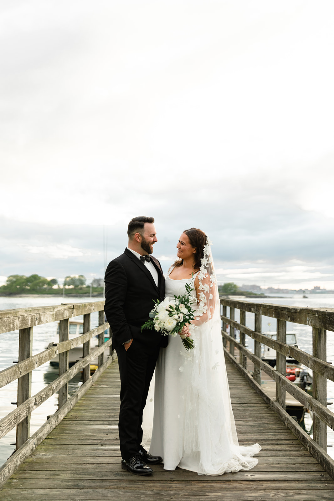 couple portraits on a pier at peaks island maine during a calm water sunset