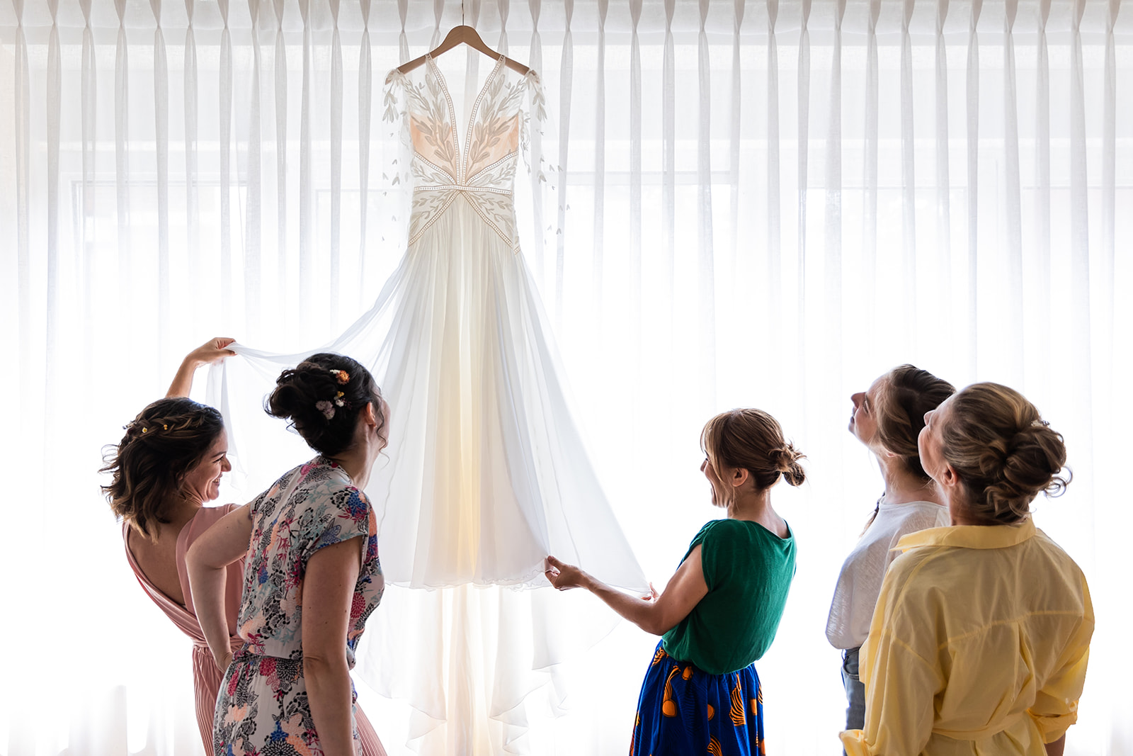 La mariée et ses amies devant la robe de mariée pendant les préparatif