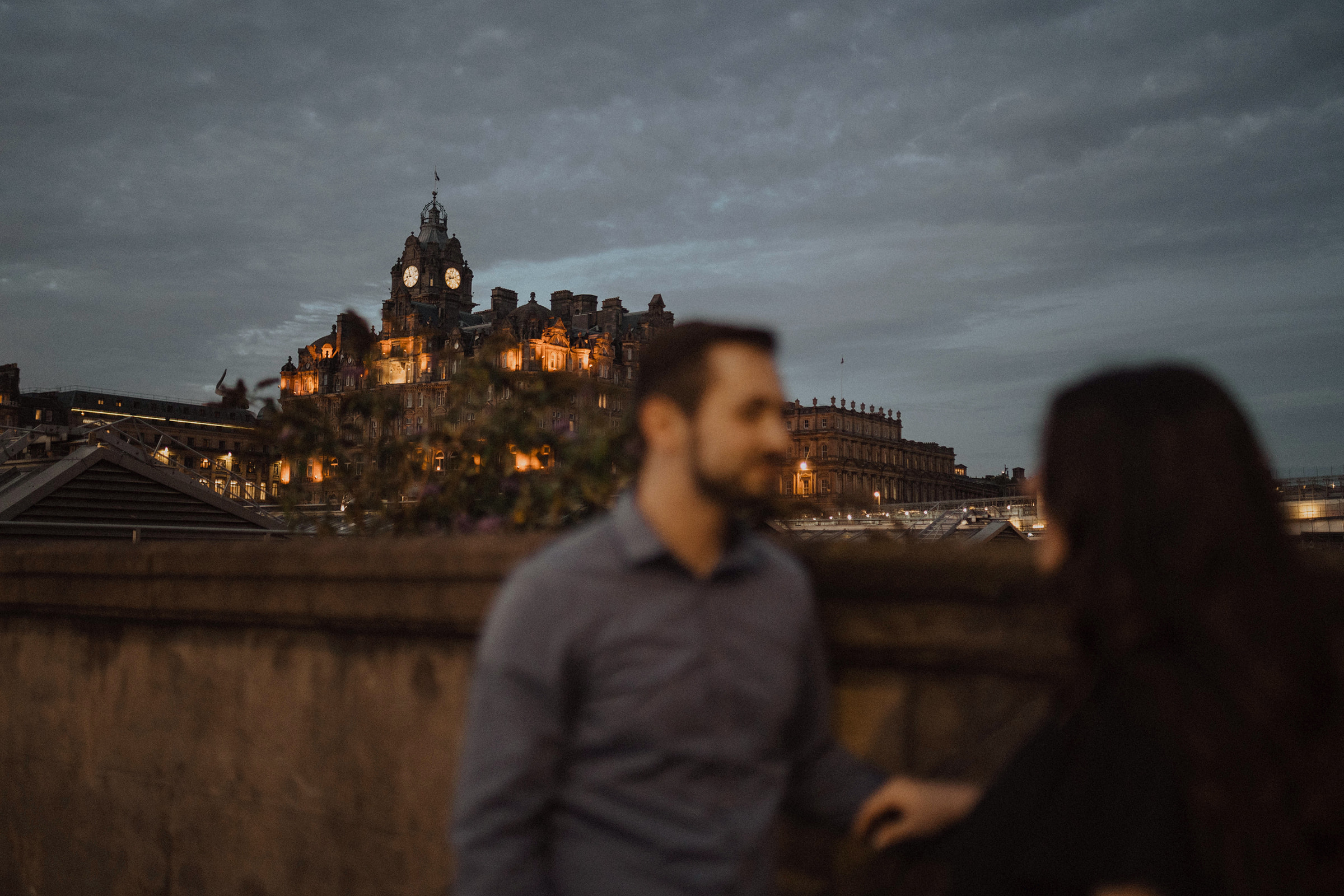 Couple in Edinburgh Old Town  look at the Balmoral Hotel together during photoshoot