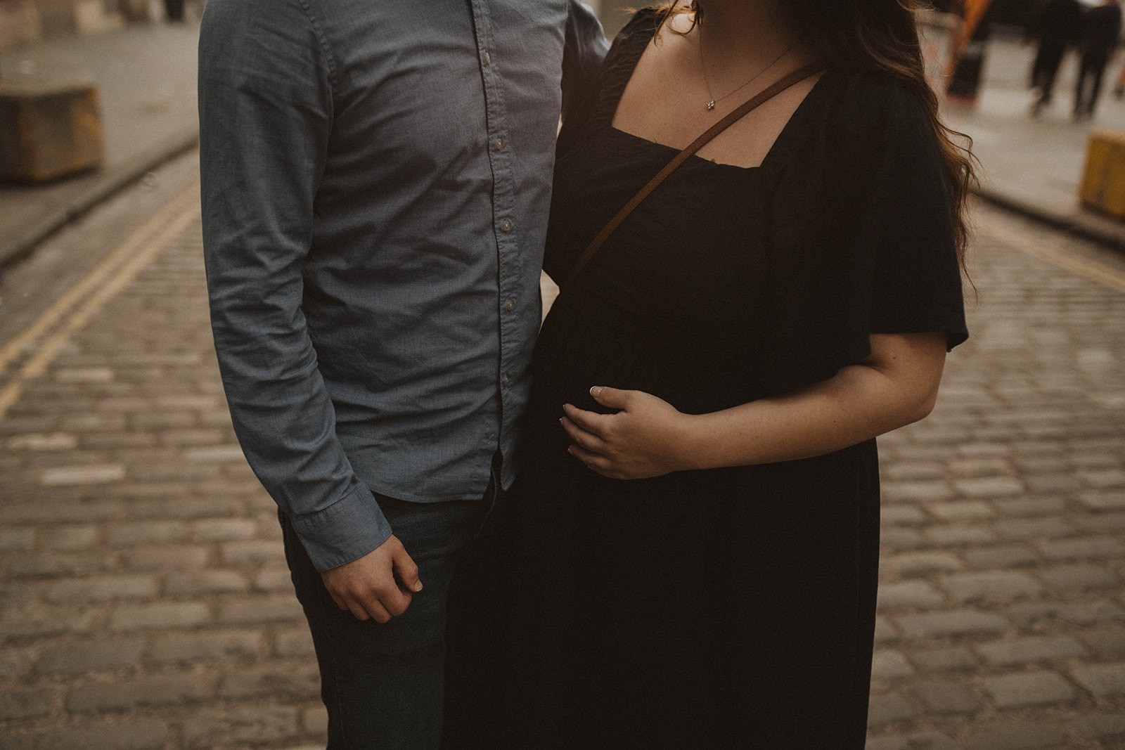 Lady holds bump and hugs her boyfriend during maternity photoshoot on Edinburgh Old Town Royal Mile photoshoot