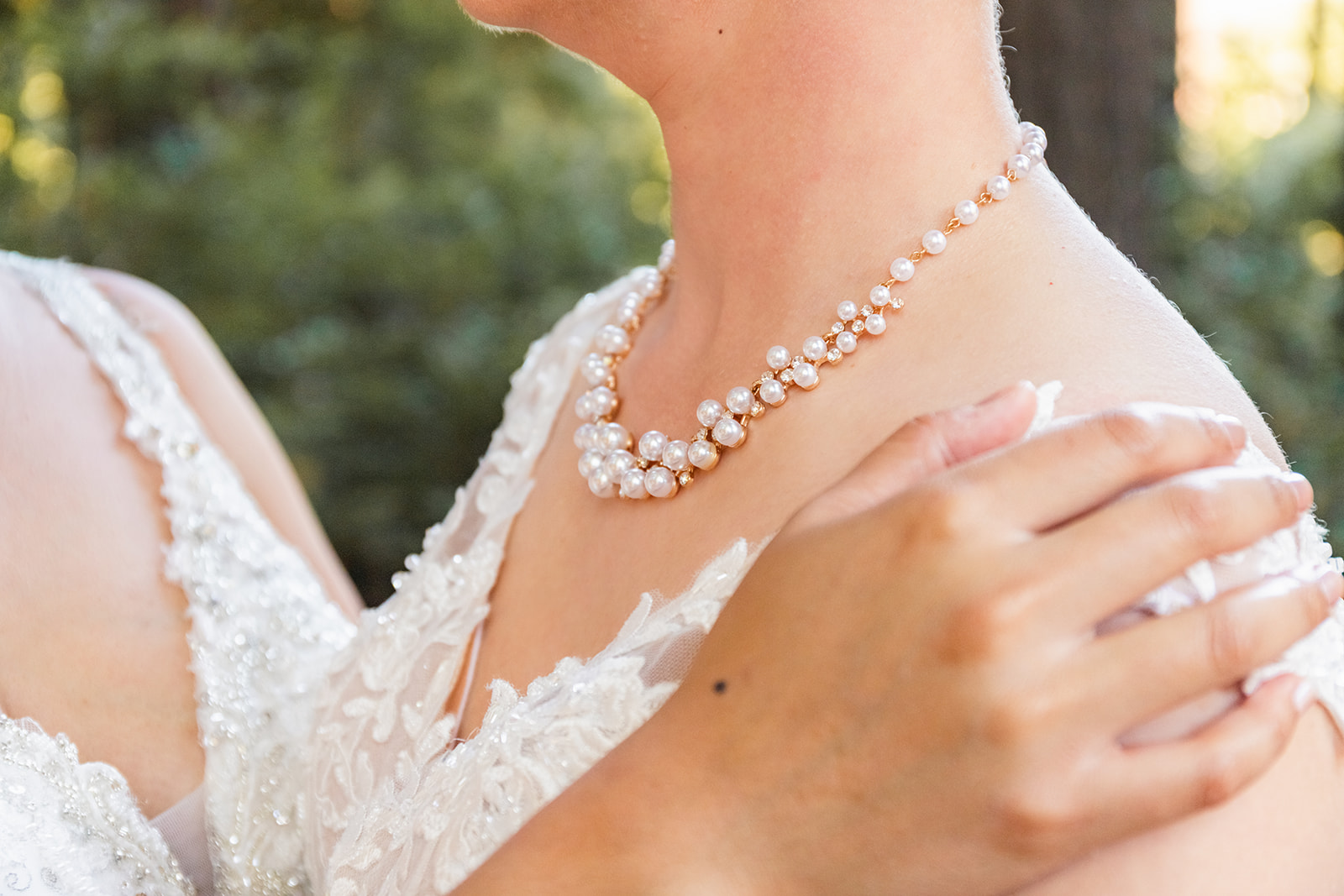 Details of pearl necklace as two brides embrace at their lgbtq+ wedding
