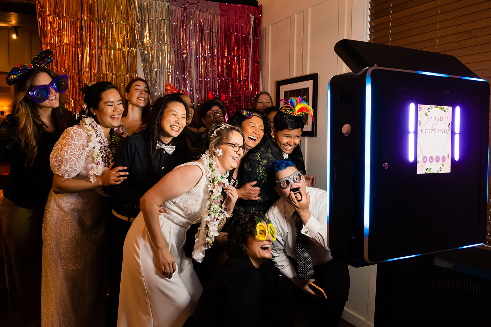 LGBTQ+ friends enjoy photo booth at wedding reception
