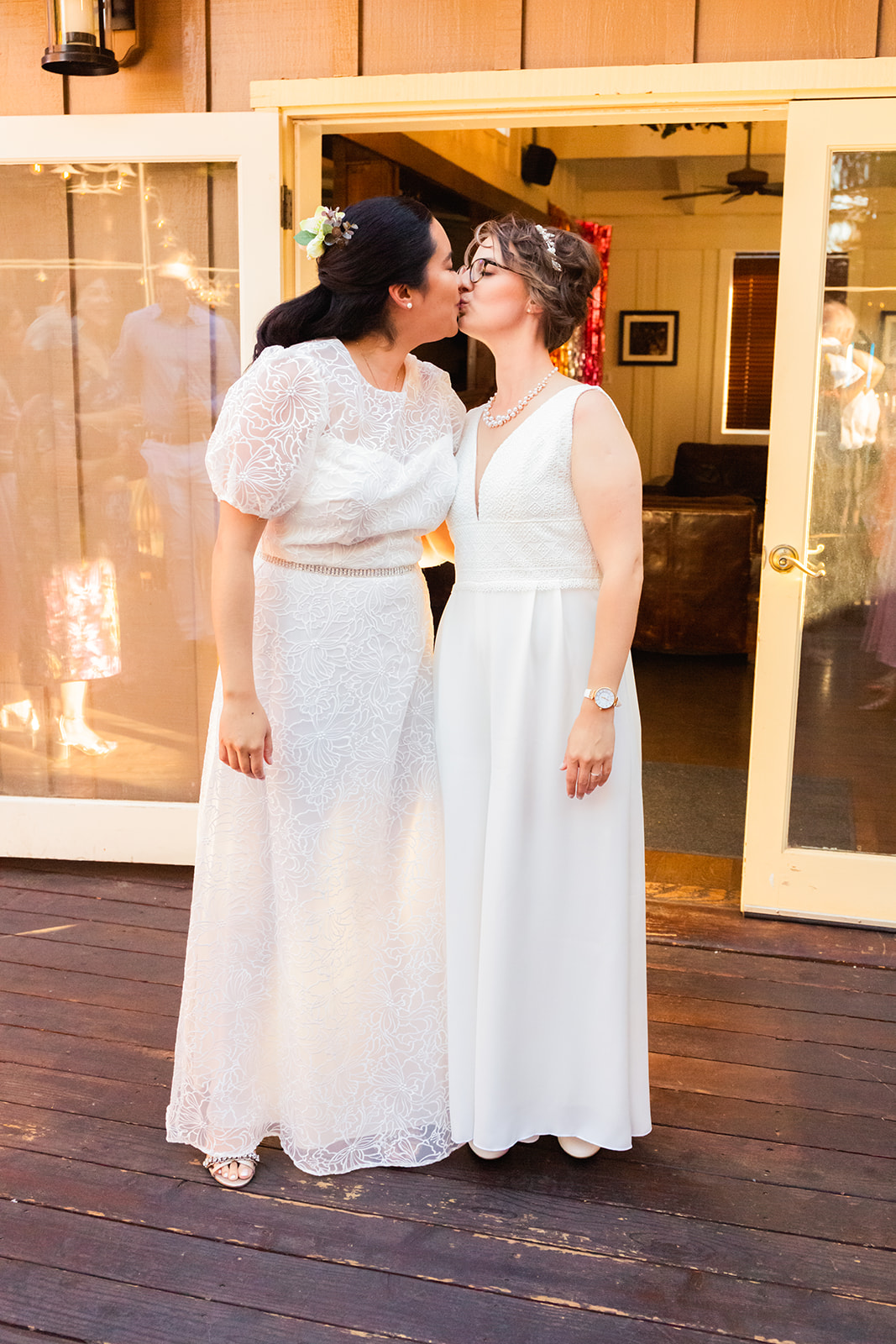 two brides kiss in their reception dresses at their lesbian wedding