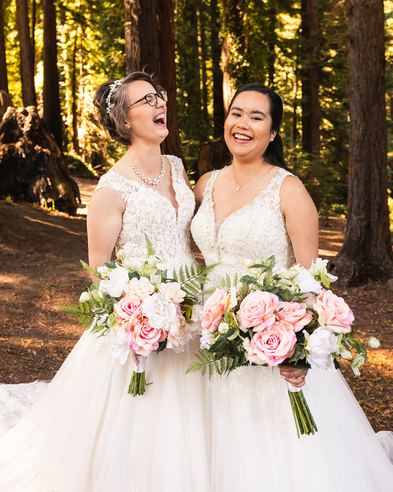 Two brides laugh while holding pink bouquets during their first look