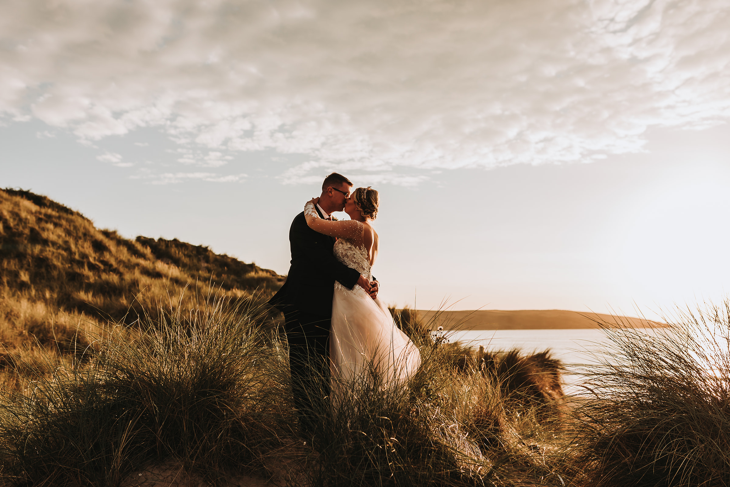 bride and groom standing on sand dune in cornwall