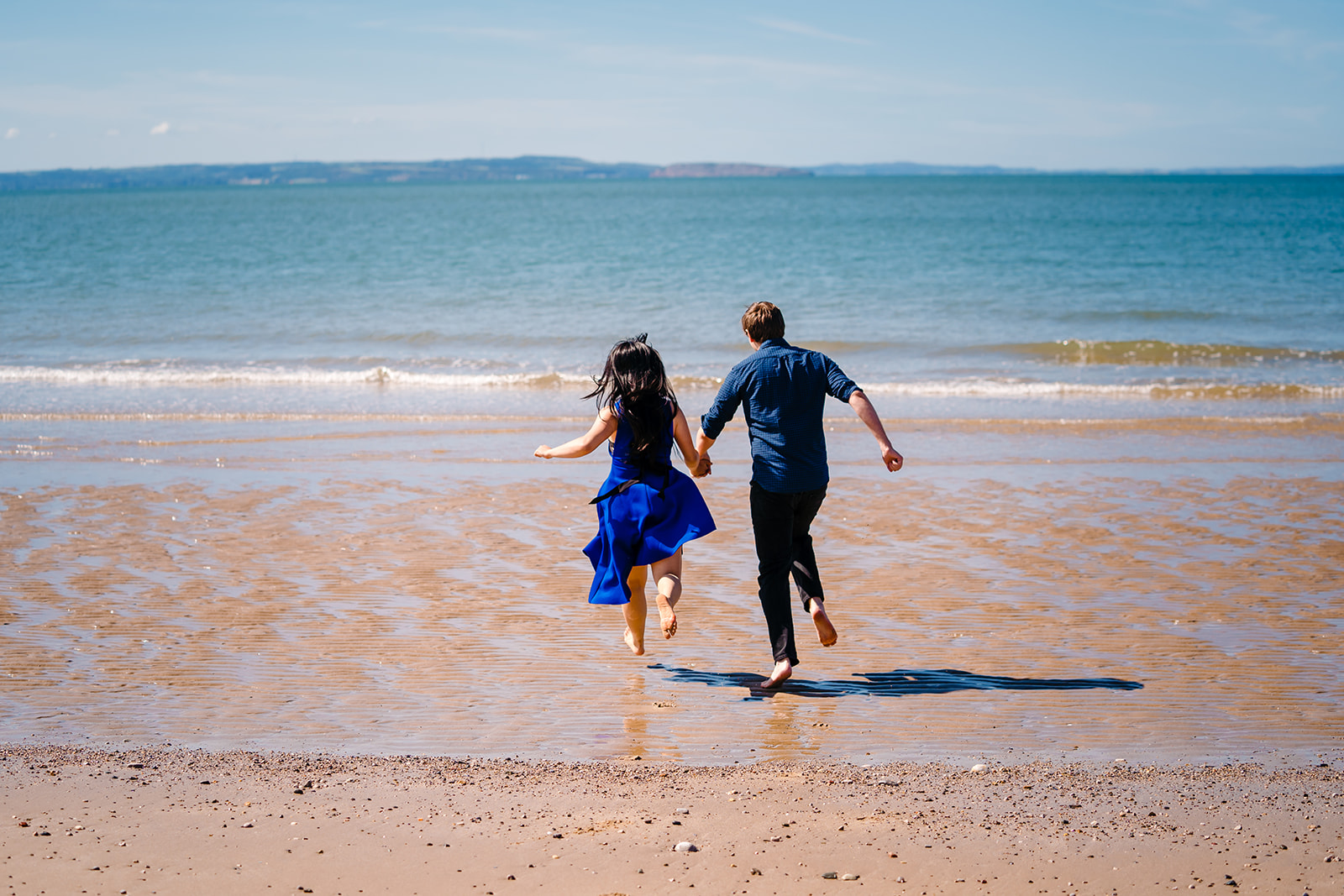 a couple running out to sea in a engagment shoot