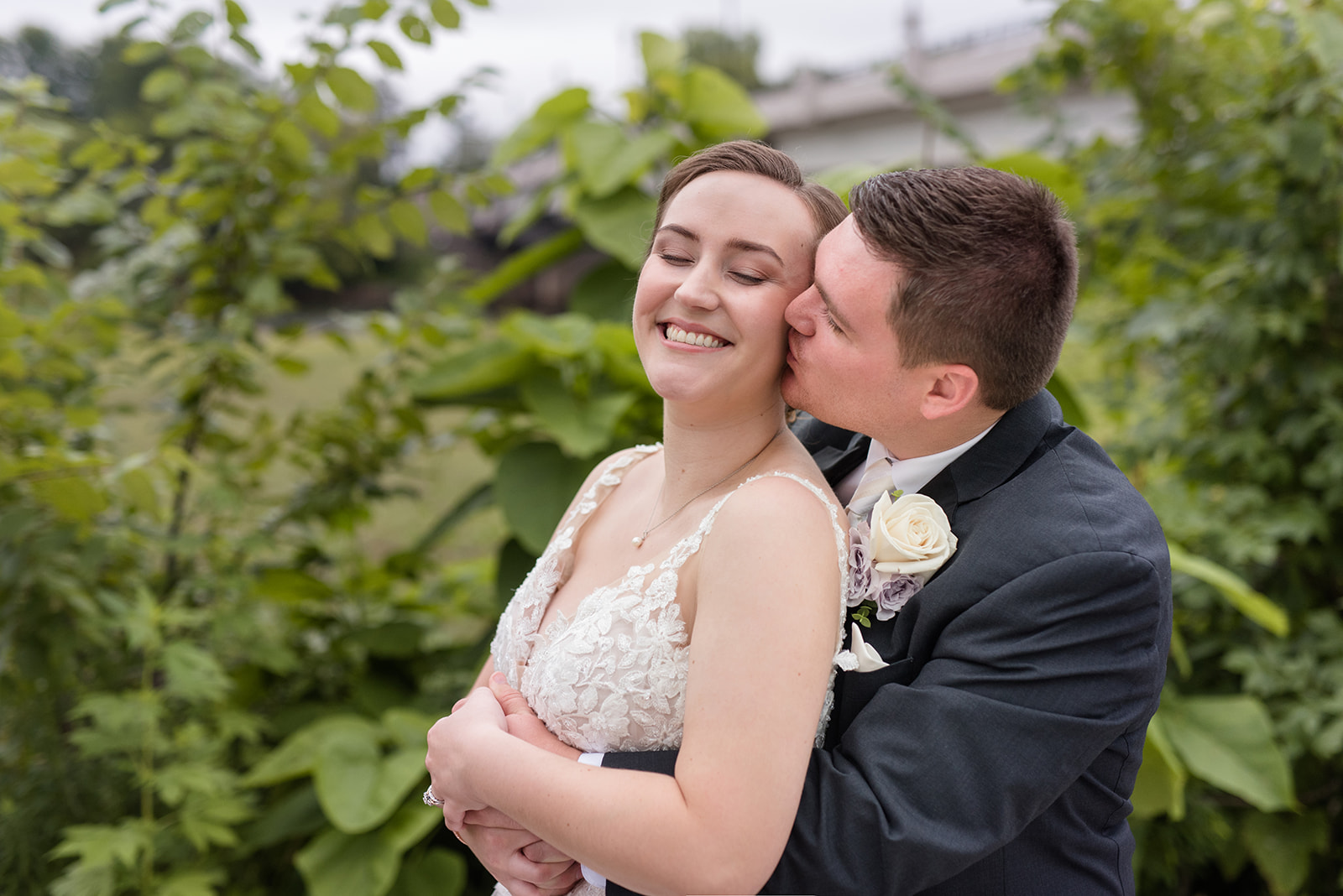 Groom surprises bride with a hug and kiss, making her laugh spontaneously