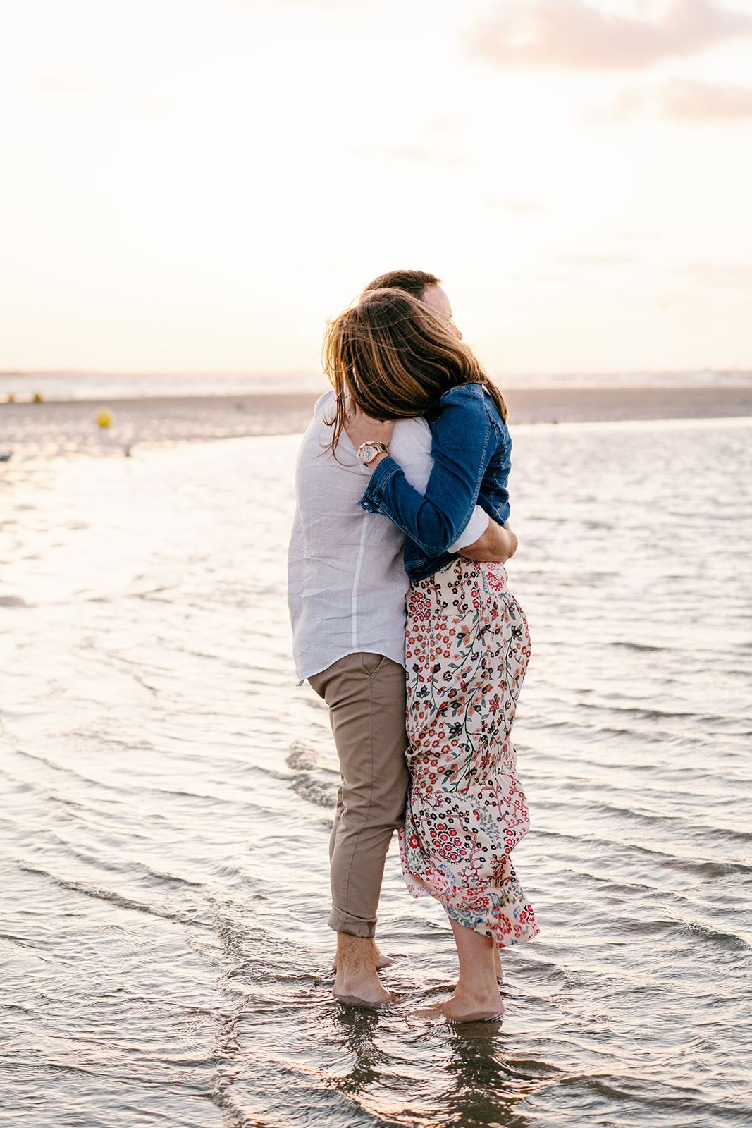 Séance couple sur la plage en Normandie, ils se câlinent les pieds dans l'eau