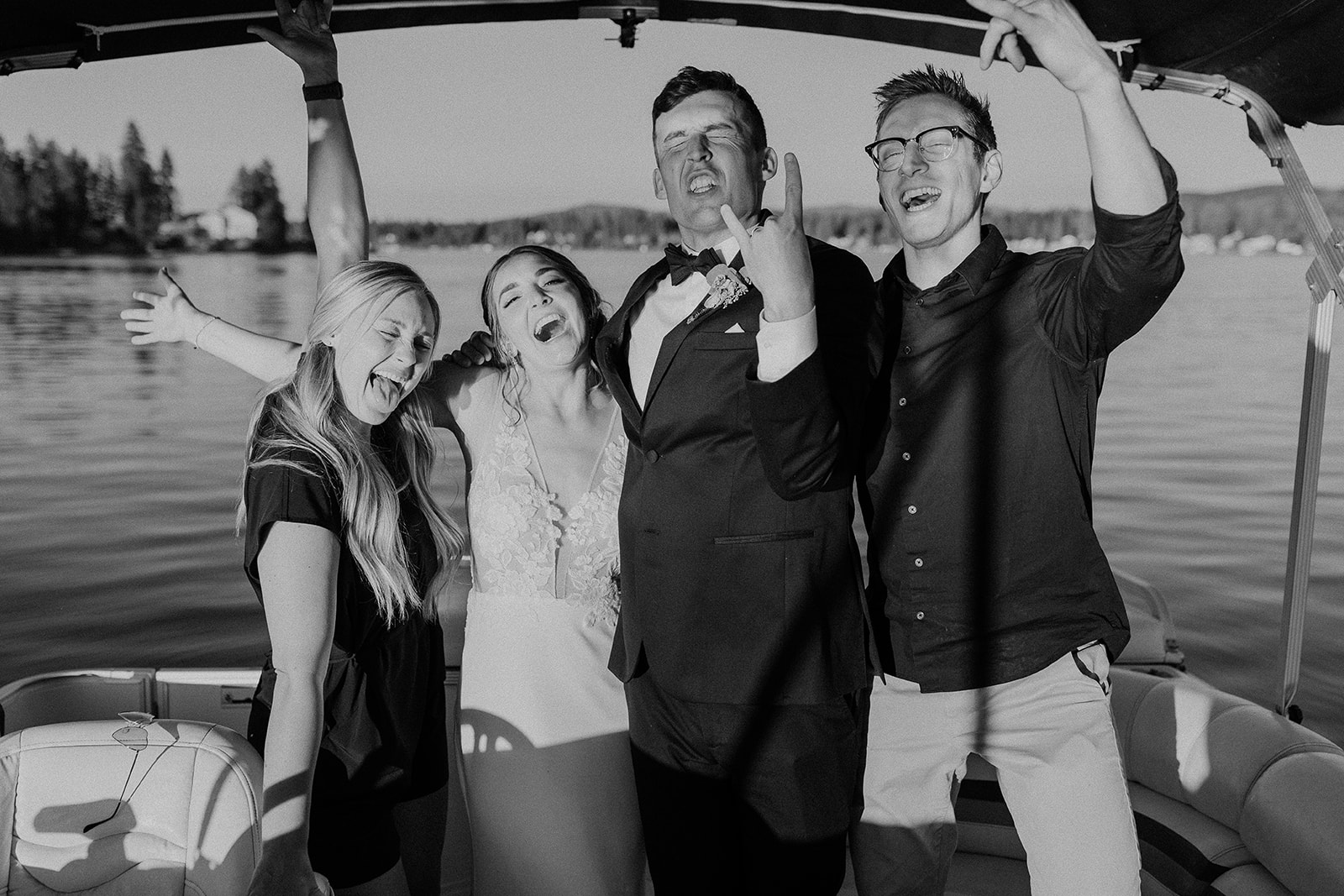 Photographer, videographer, bride and groom snap a photo together on pontoon boat at private lake house wedding. 