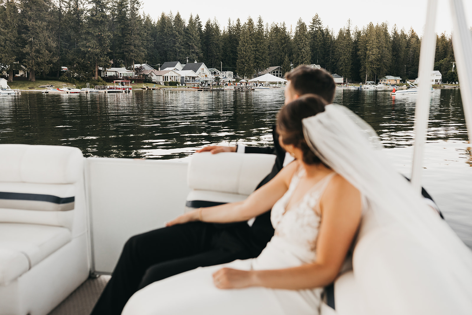 Bride and groom riding around on the family pontoon boat at private lake house wedding.