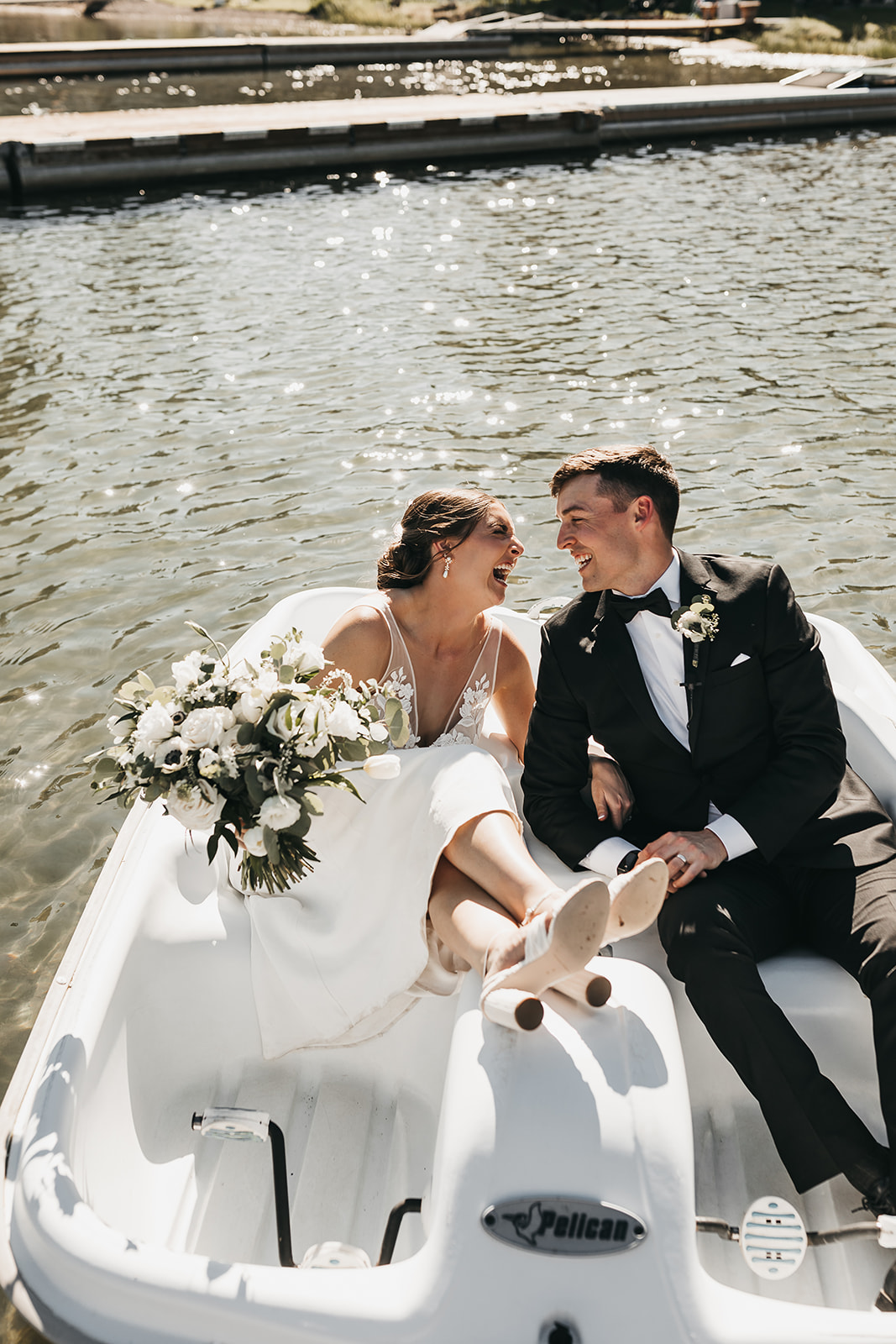 Bride and groom sitting in paddle boat on the lake at lake house wedding.