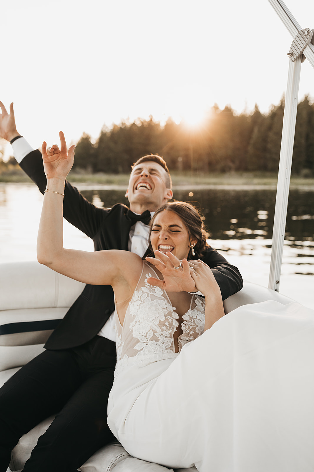Bride and groom having fun on the family pontoon boat at private lake house wedding.