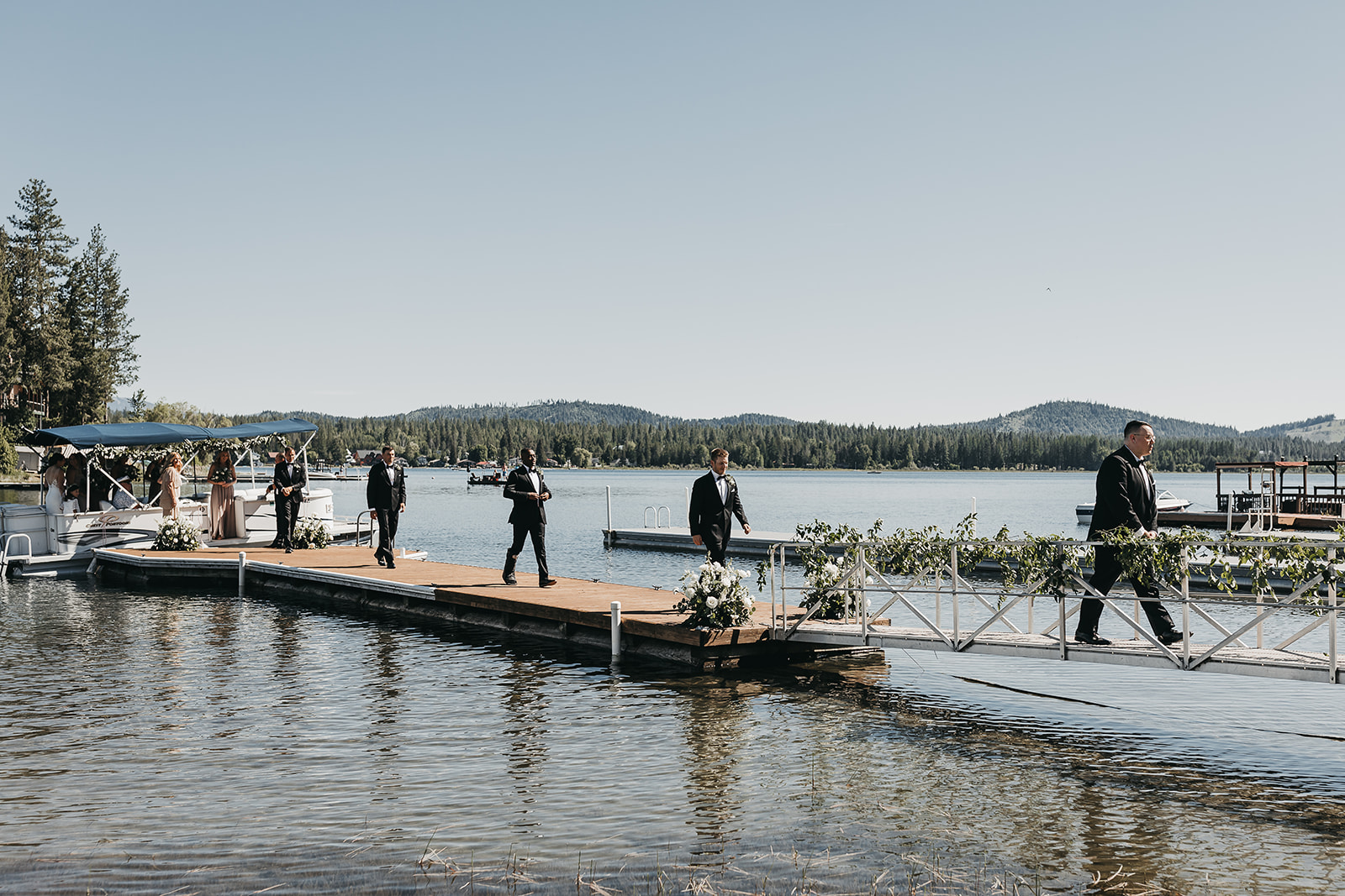 Wedding party getting off pontoon boat on to the dock at a private lake house wedding.
