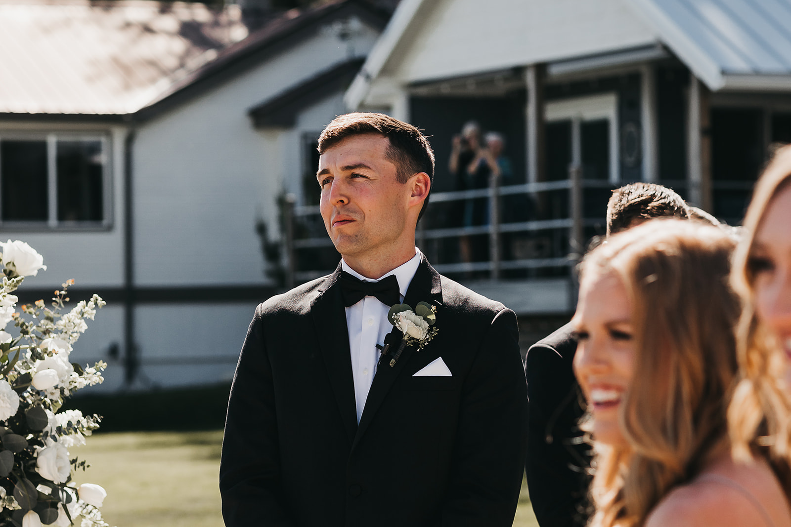 Groom getting emotional at bride walking down the aisle at private lake house wedding. 