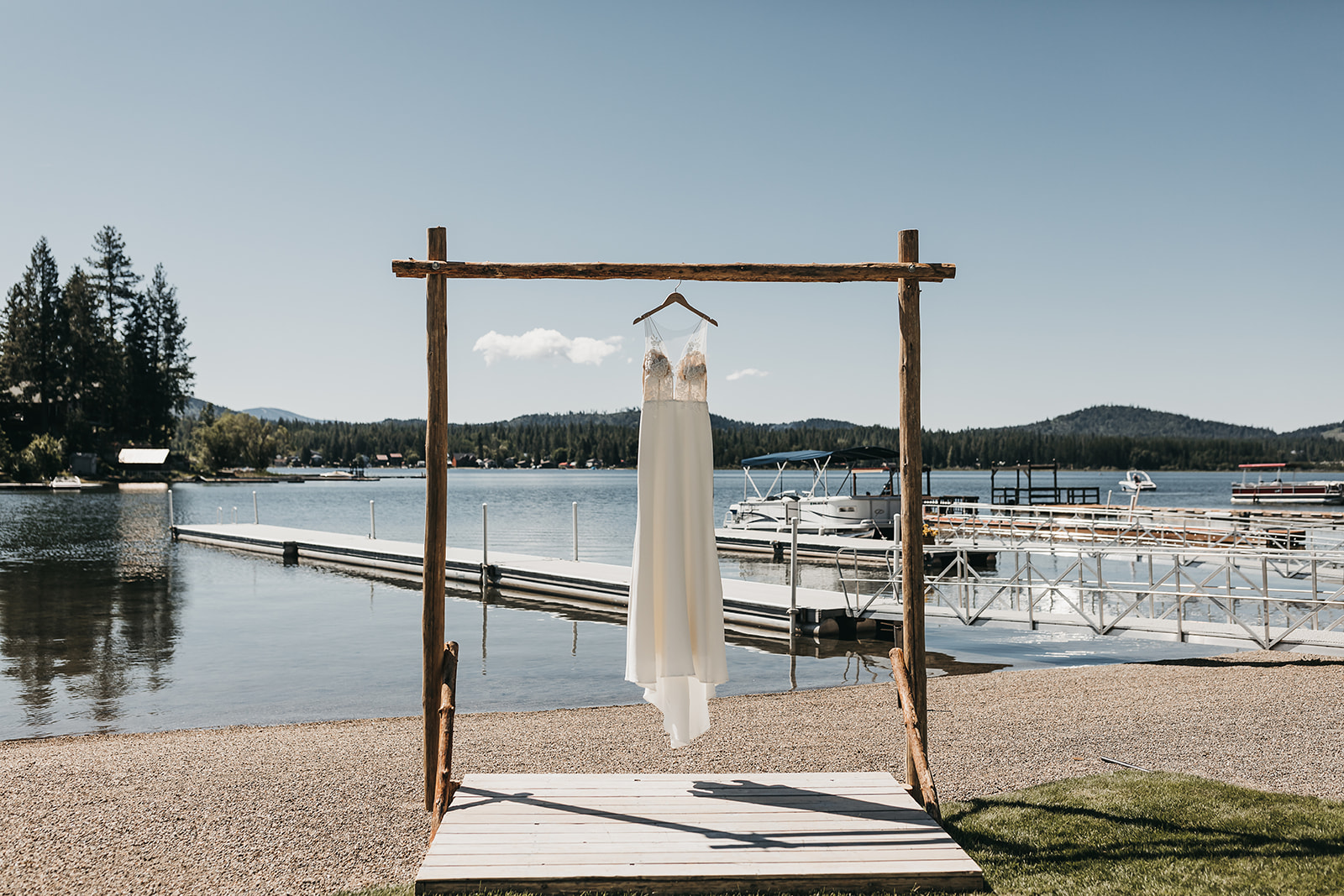 Bridal gown from Anna Kara hung under arch way for wedding ceremony. With private dock lake house views
