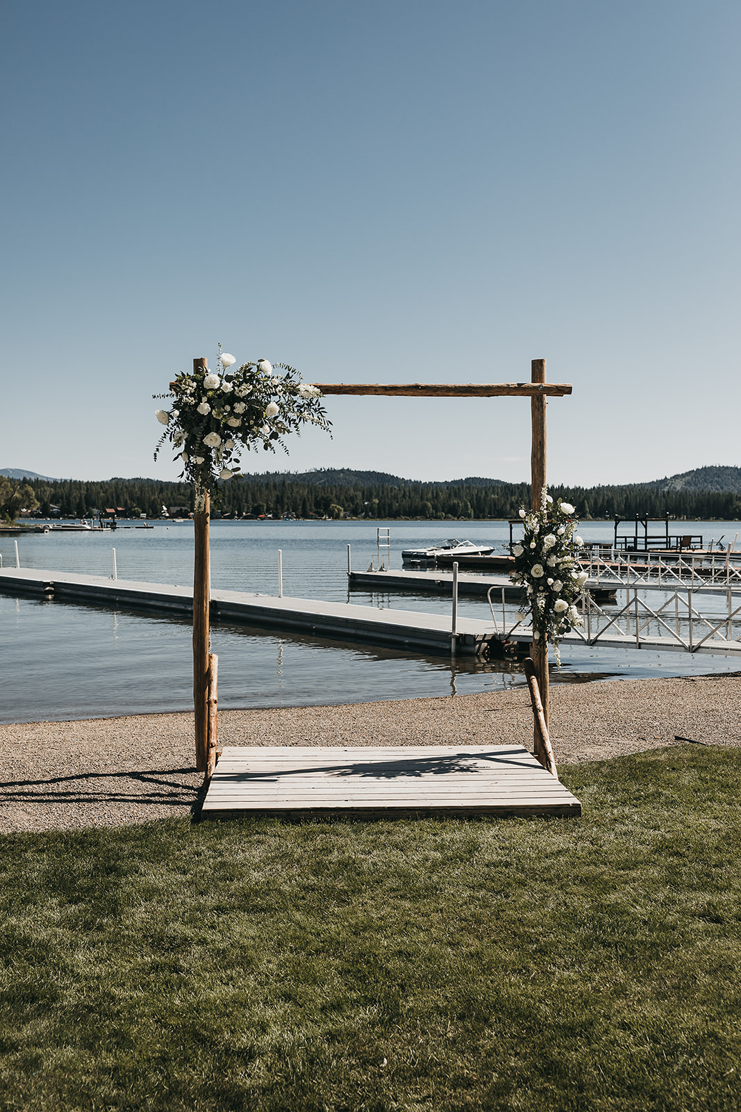 Arch way for wedding ceremony. With private dock lake house views. And florals by Emily McBride.