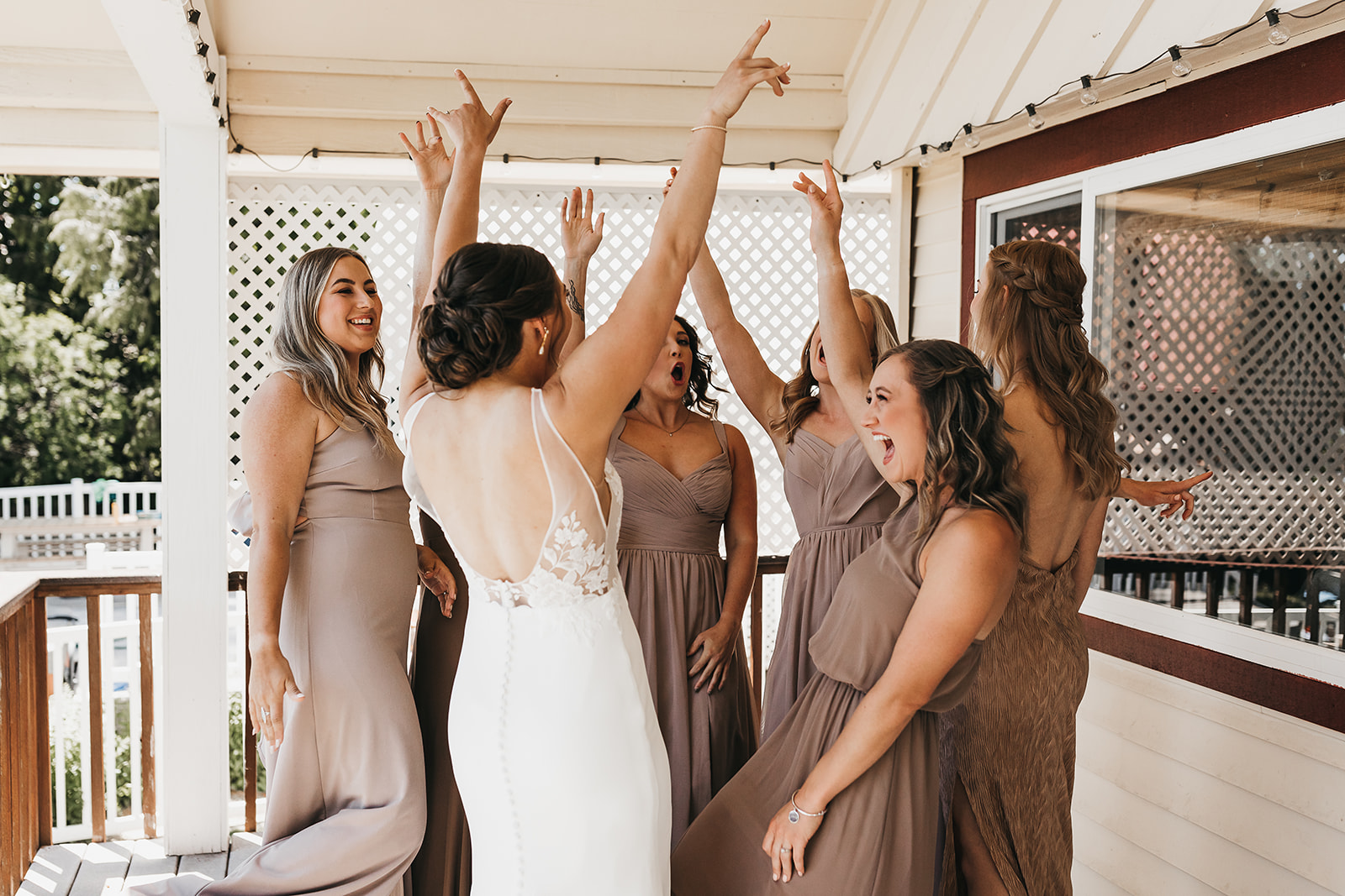 Bridesmaids getting excited and celebrating with the bride before the wedding ceremony at private lake house.