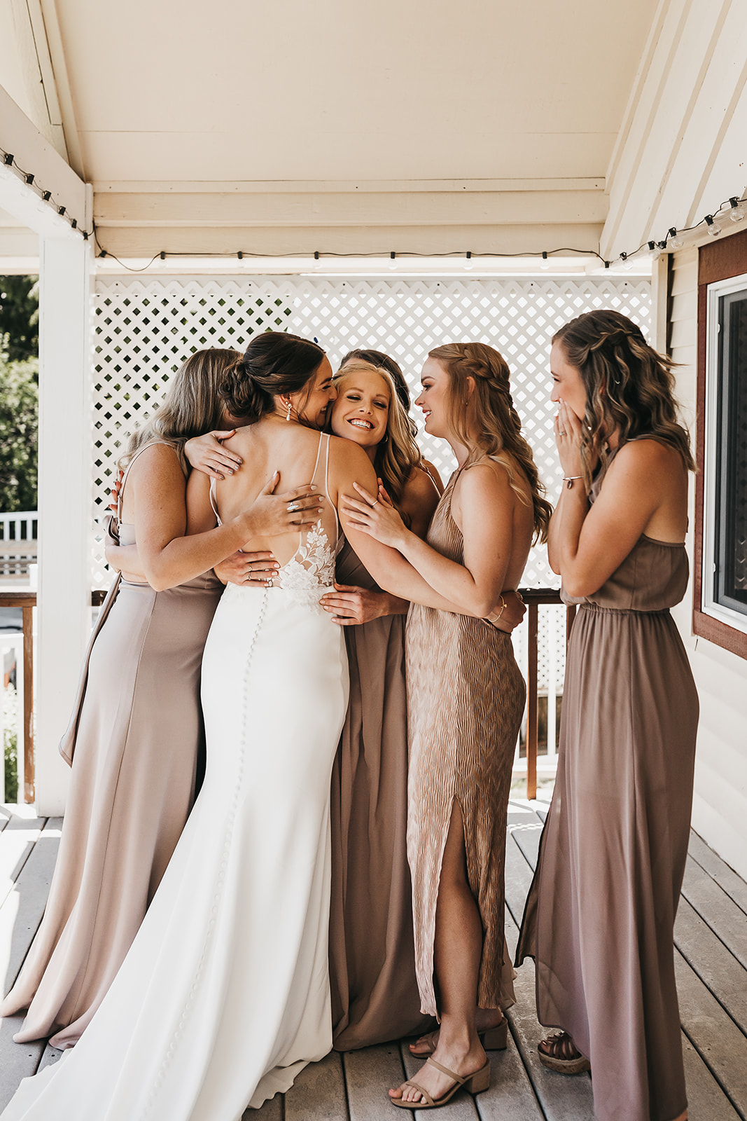 Bridesmaids embrace the bride at first look of bride at private lake house wedding.