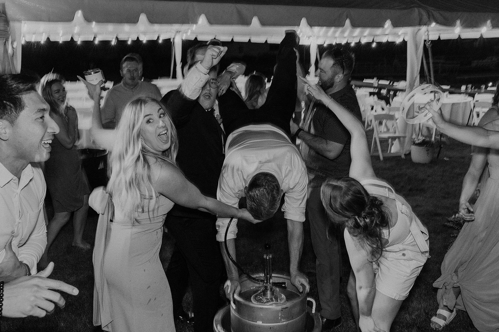 Wedding guest doing keg stand during wedding reception at private family lake house. 