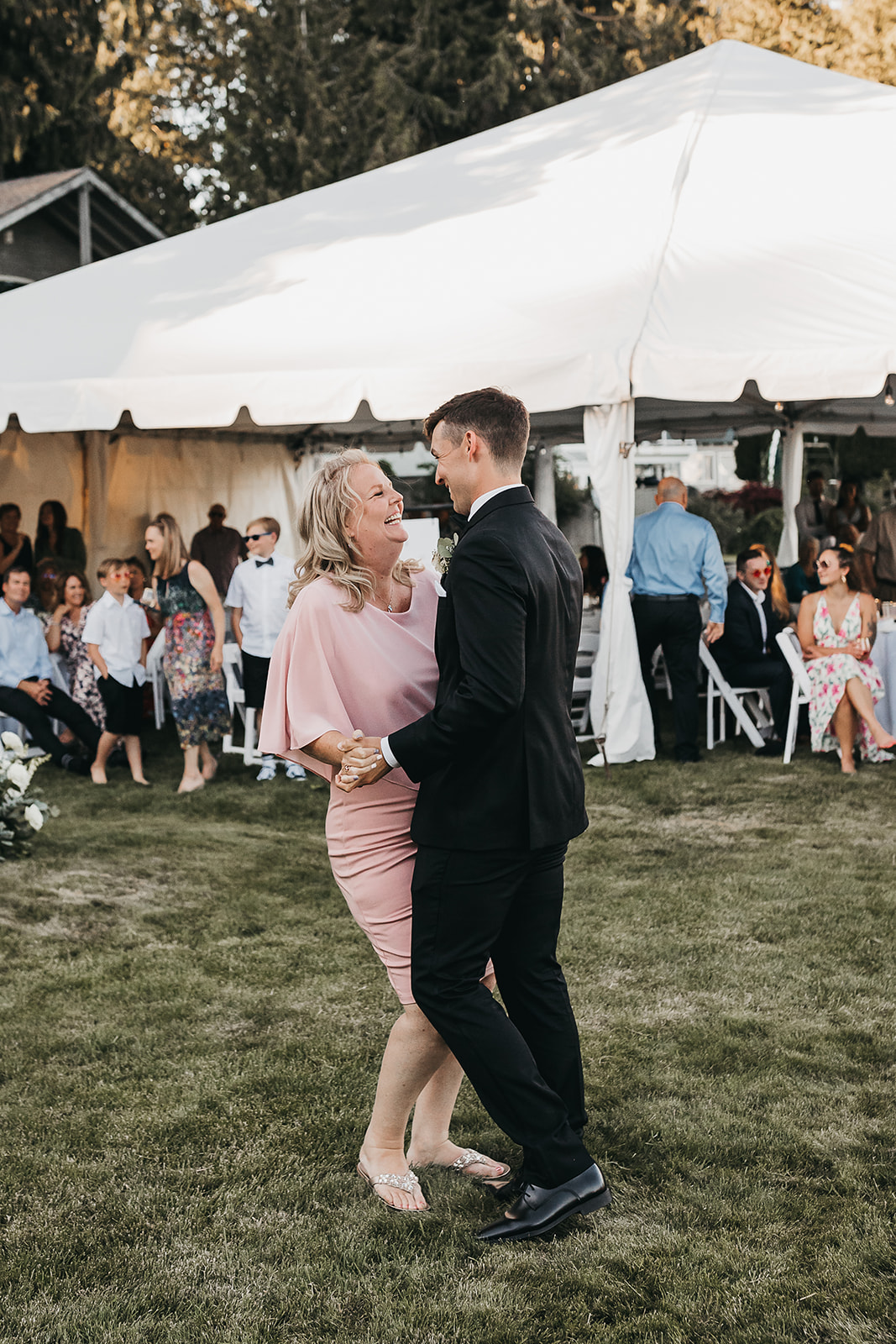 Groom and mother of the groom share a dance at the wedding reception at private lake house. 