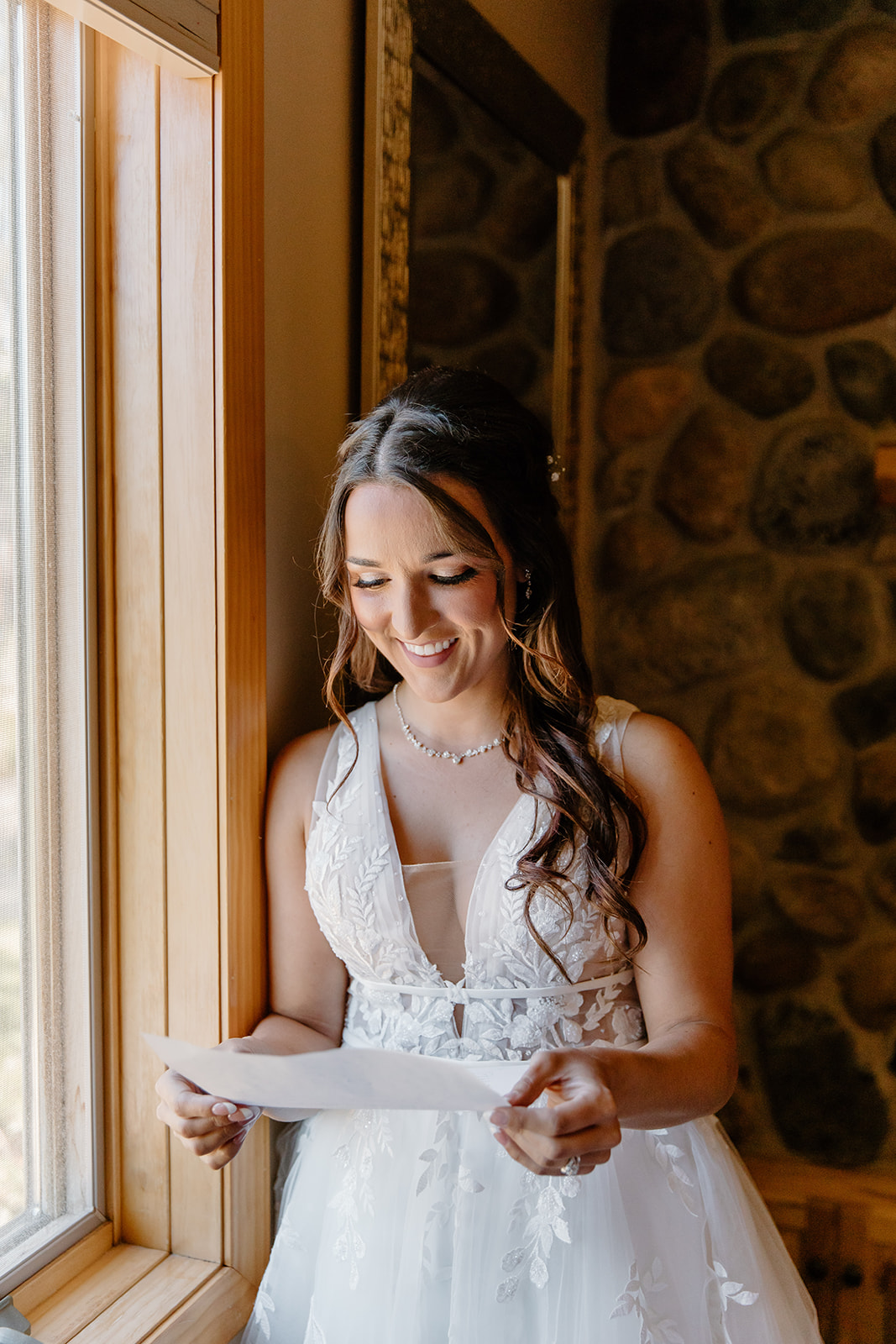 Bride reads a letter in front of a window