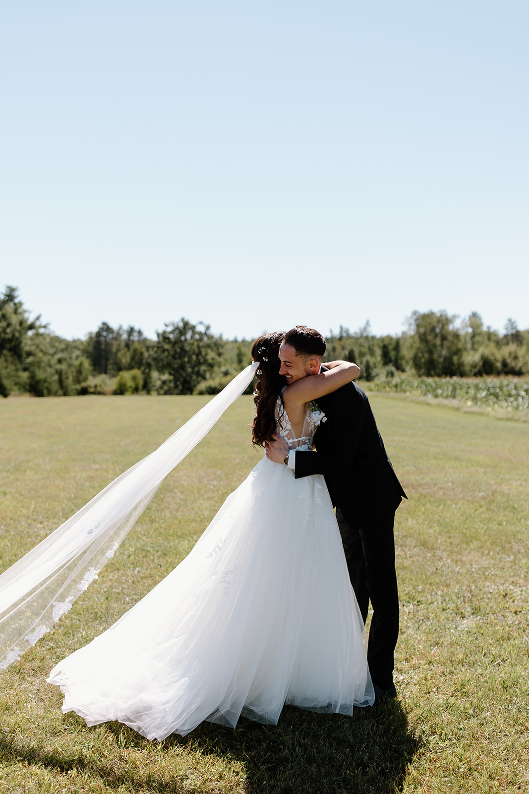Bride and groom hug in an open field