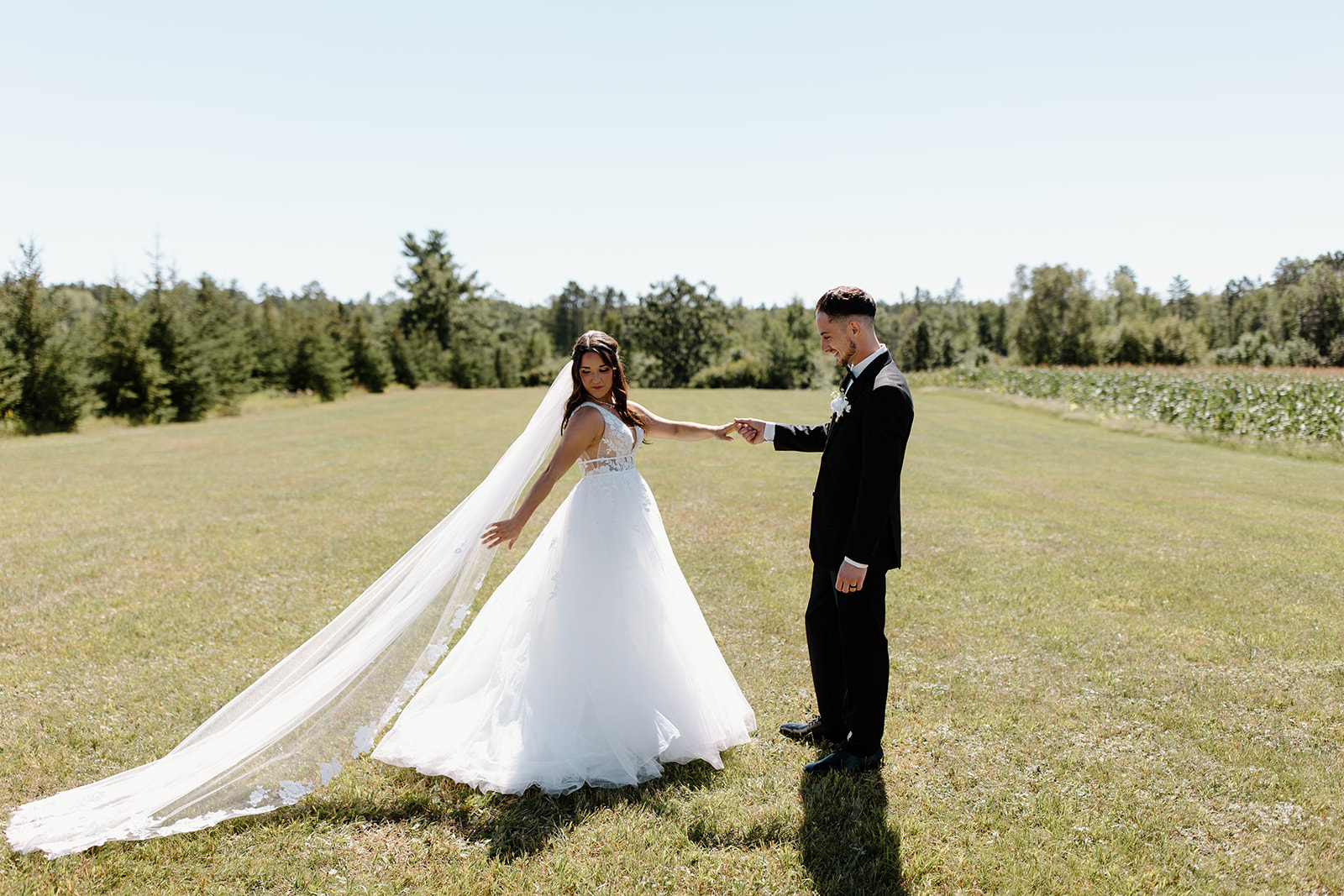 Bride and groom hold hands in an open field