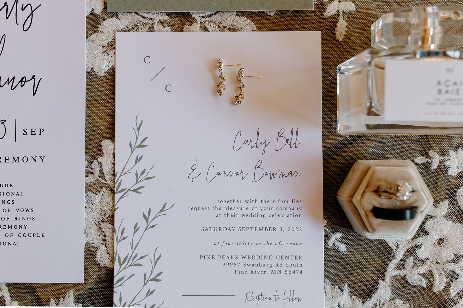 Flat lay of wedding invites, rings, and jewelry