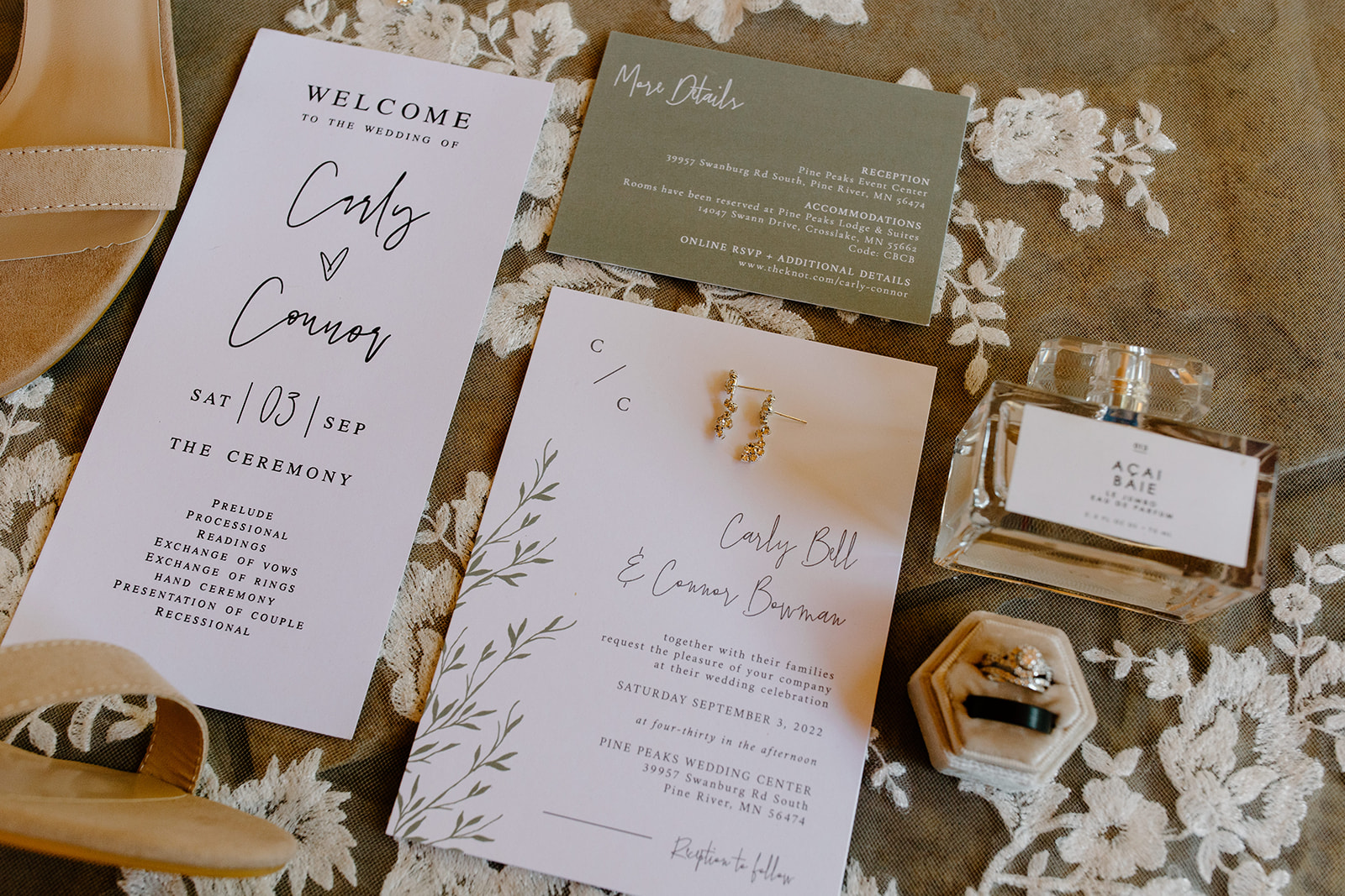 Flat lay of wedding invites, rings, and jewelry