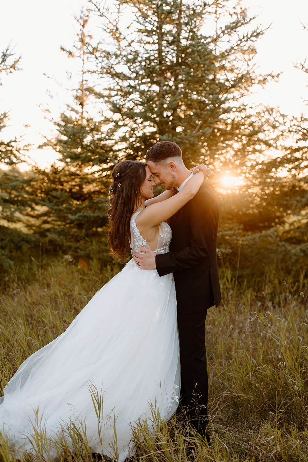 Bride and groom hug in front of the sunset