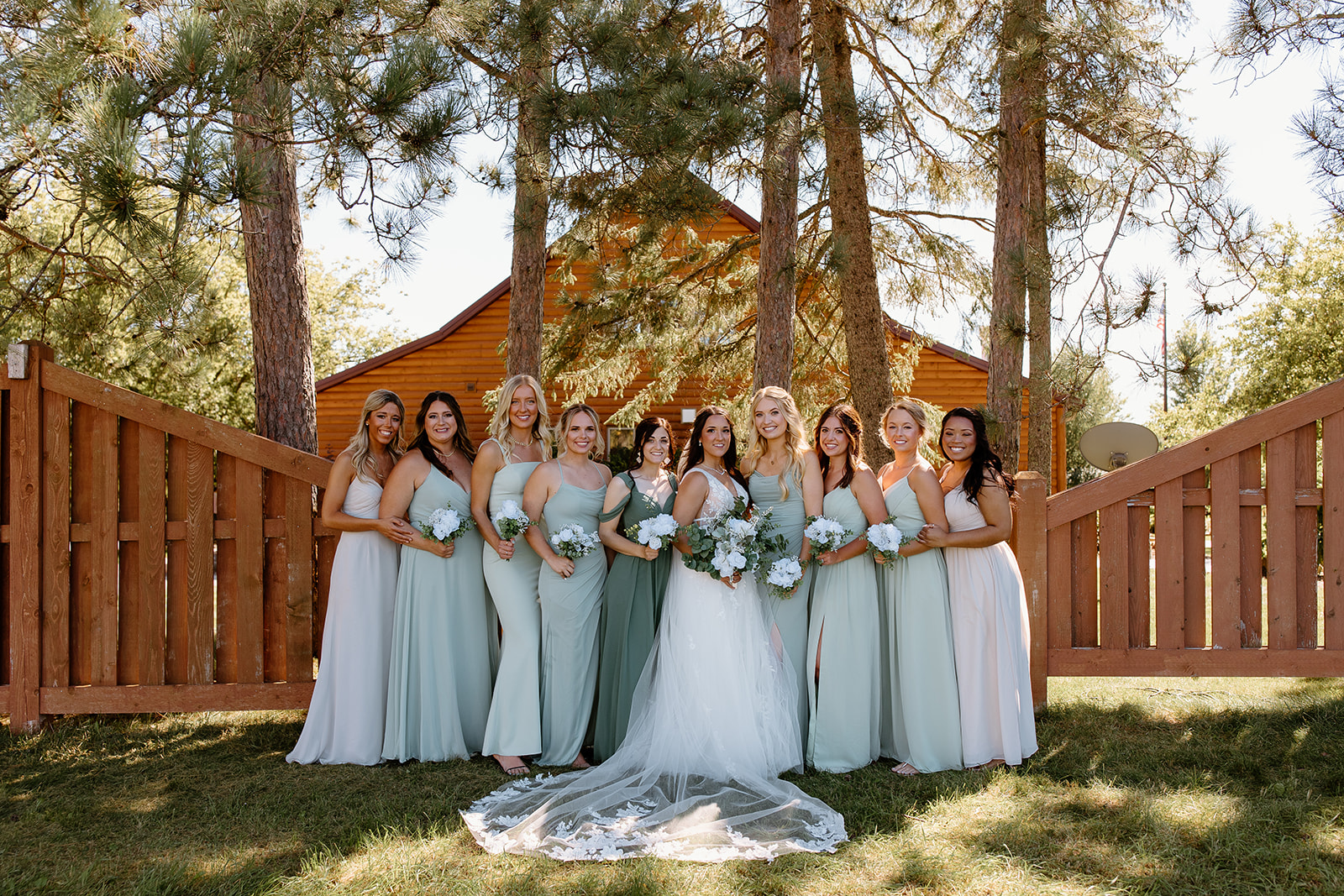 Bridesmaids smile in a line in front of the camera